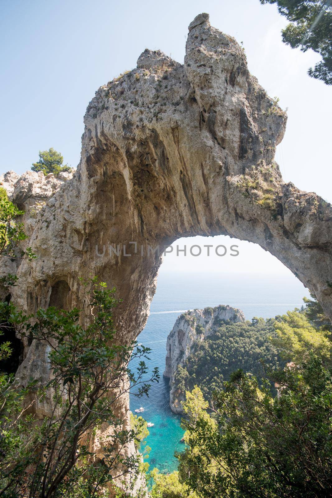 View of natural rock arch with the sea in the background. Vertical framing. Capri island, Italy.