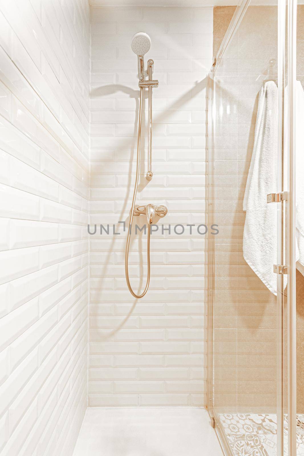 Vertical image of shower zone in a white, beige hotel bathroom. Concept of vacation, hotel.