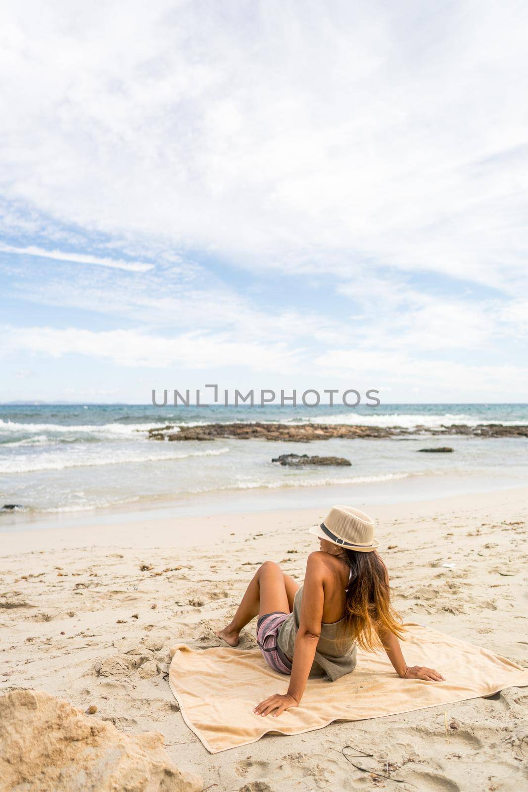 Pretty woman sunbathing on the beach. Long shot. Formentera island, Spain.