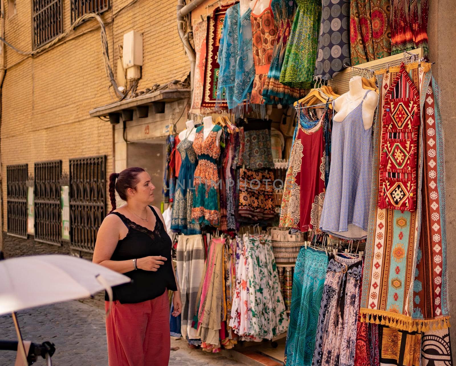 Lifestyle shopping concept, young happy caucasian woman choosing clothes in store on shopping street at daytime. stock photography