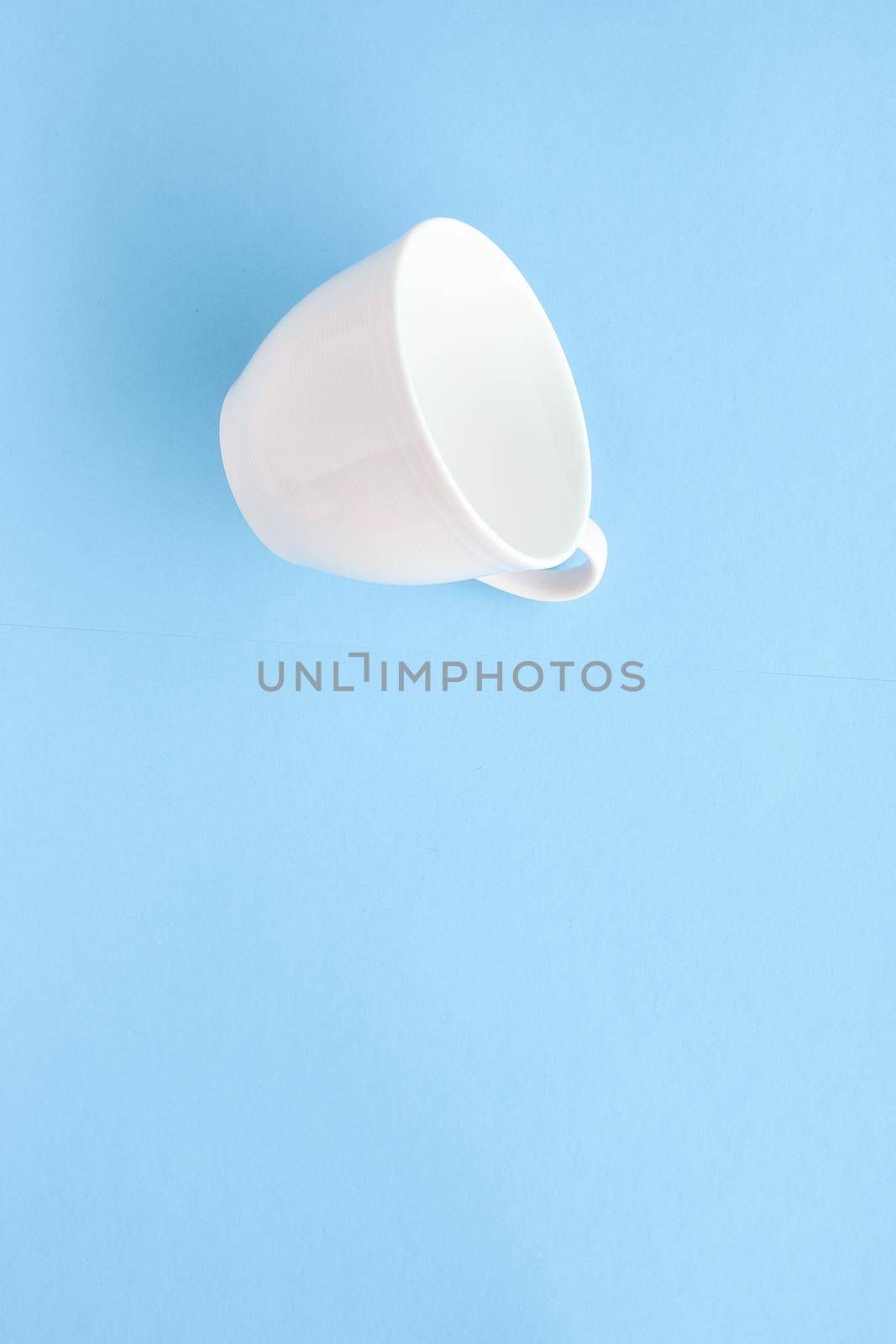 Empty cup and saucer on blue background, flatlay by Anneleven