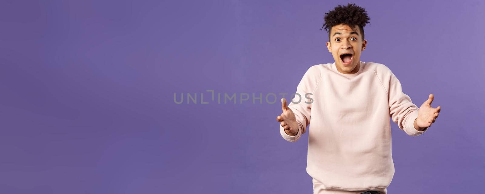 Portrait of surprised happy young man reaching hands to hug friend seeing him on street, rejoicing over big great news, standing impressed and thrilled over purple background by Benzoix