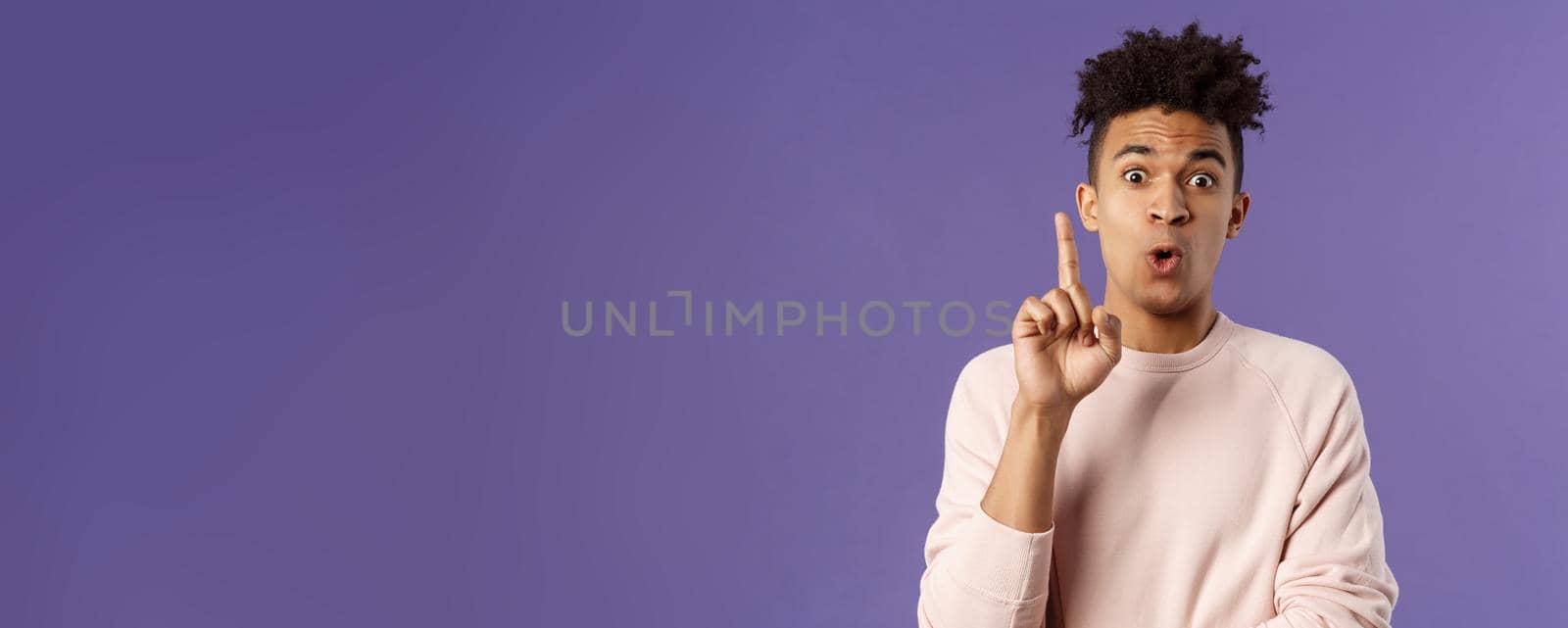 Got it, have plan. Portrait of excited happy young man, rejoicing as being striked with great idea, raise index finger in eureka gesture, figured out something, have suggestion, purple background.