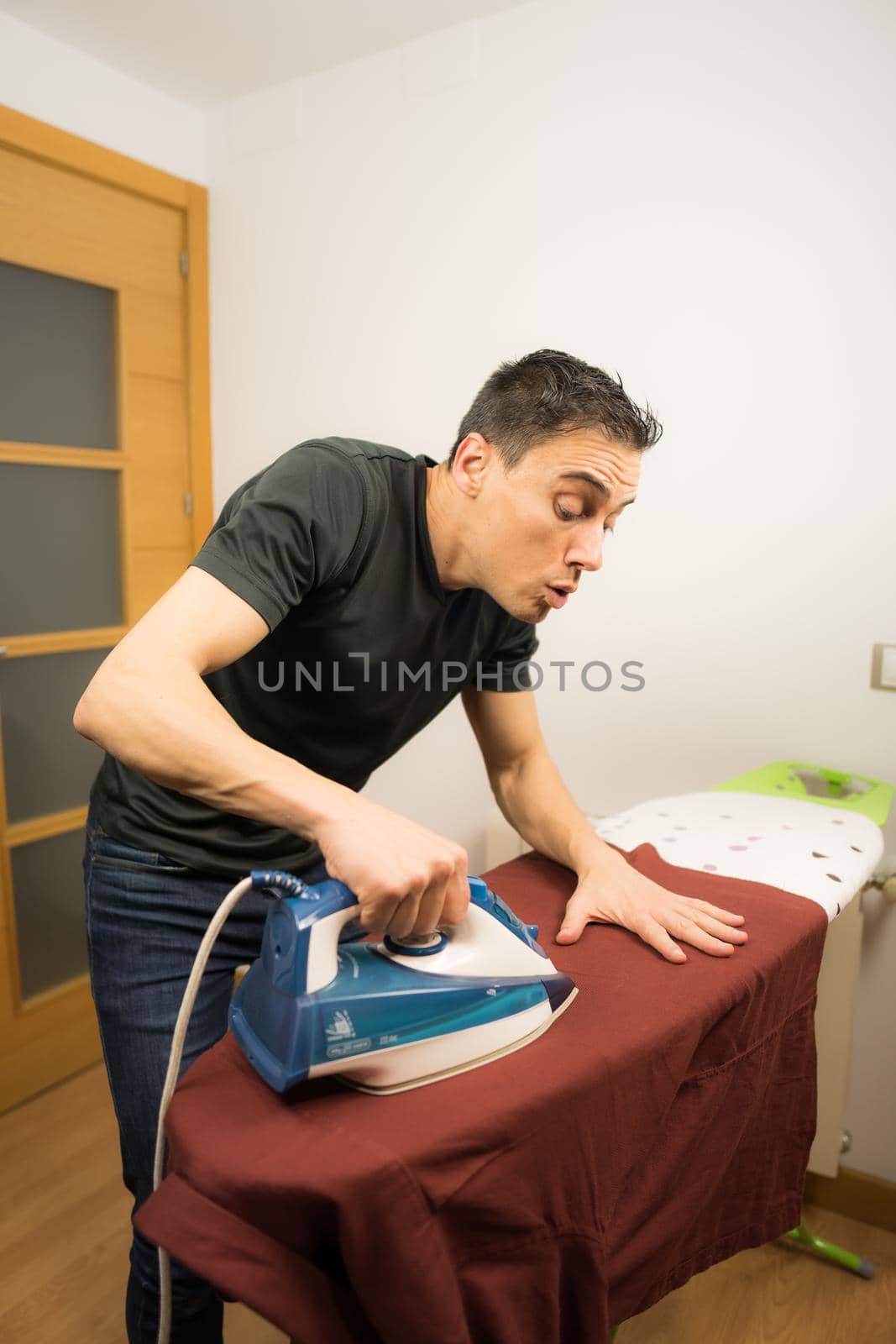 Man ironing a shirt at home with extreme care. Mid shot.