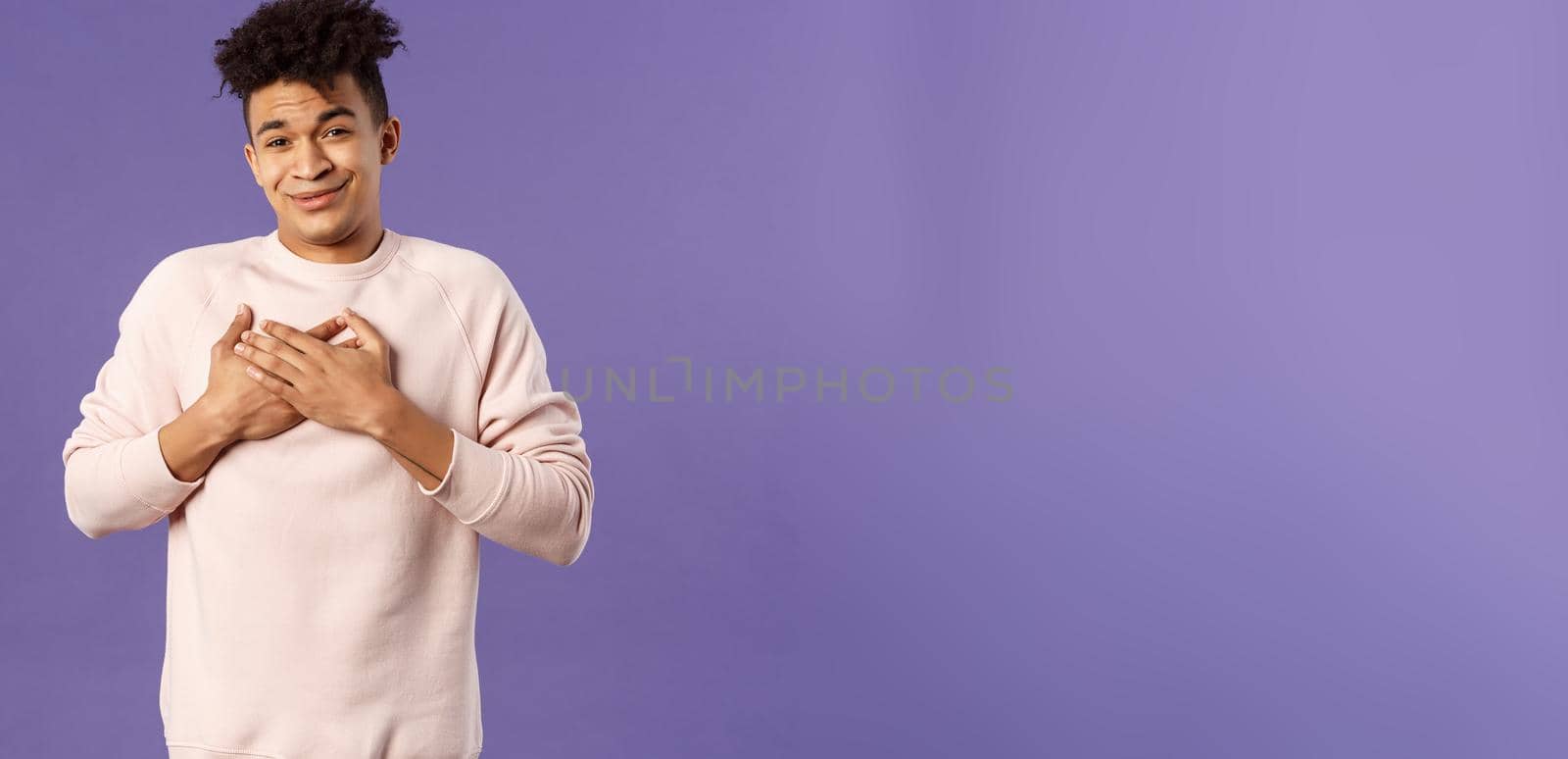 Portrait of touched silly young man left speechless and flattered, sobbing as being hit right into heart with dear warm words and praises, pleased standing purple background.