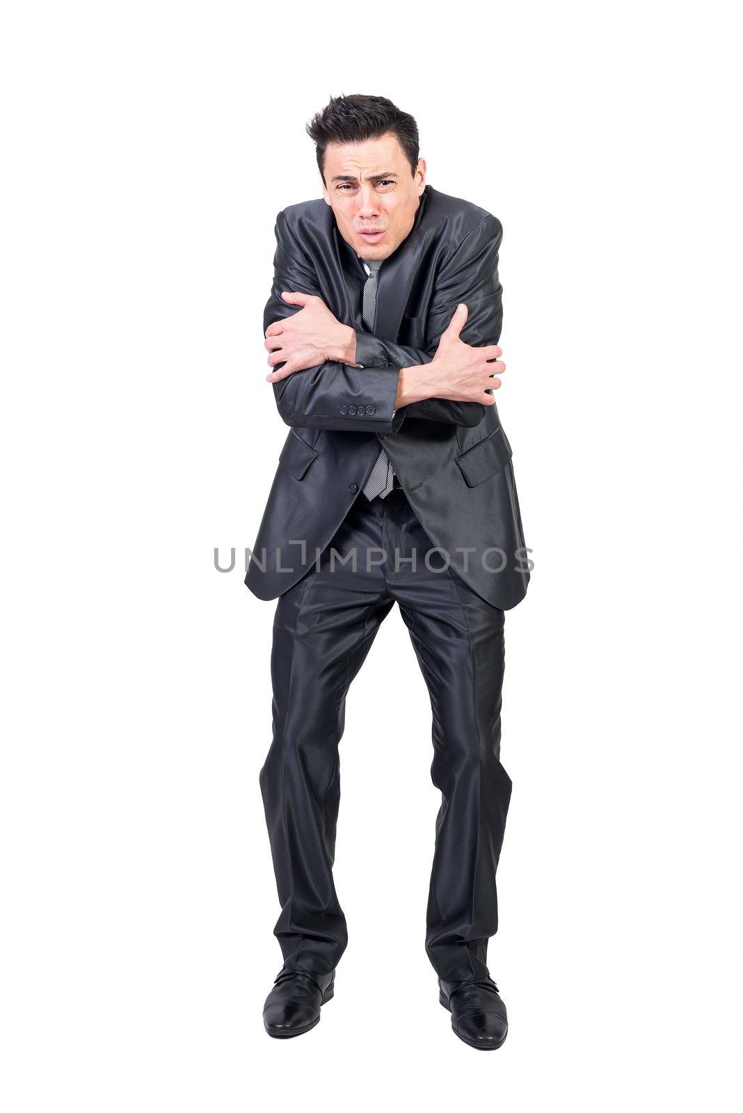 Full body of male in suit embracing himself and feeling cold on white background in studio while looking at camera