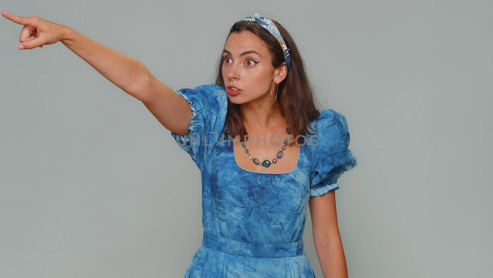 Get out of here. You are fired. Dissatisfied young woman pointing finger away asking to leave her alone, strict boss firing, conflict, crisis, deadline. Adult stylish girl on gray studio background