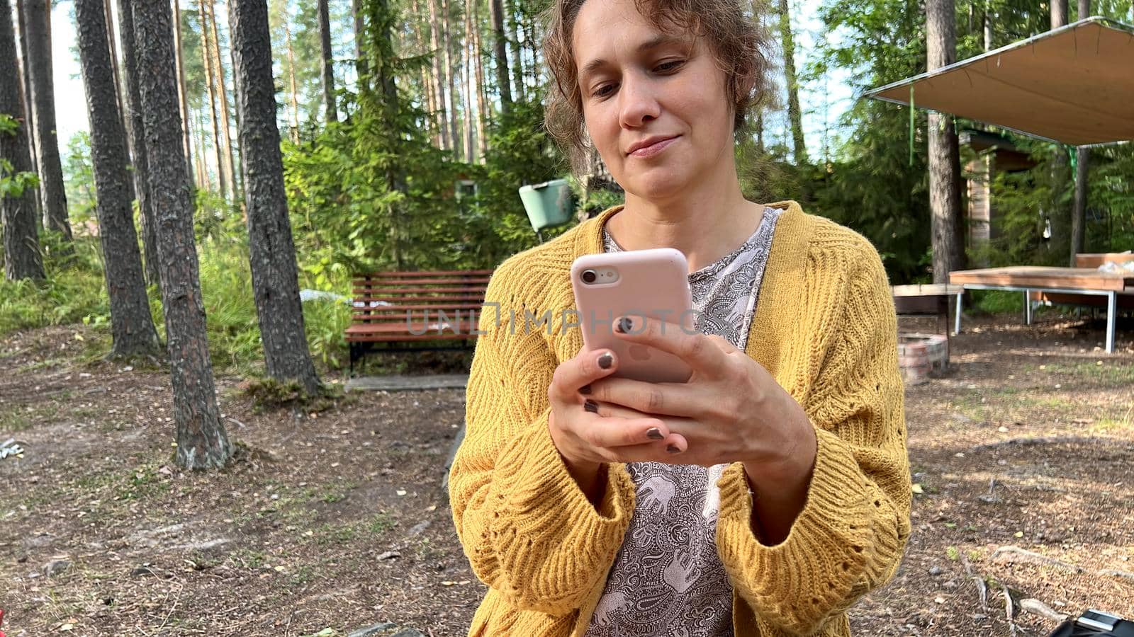 Mid-aged beautiful woman using her smart phone in the forest. High quality vitro