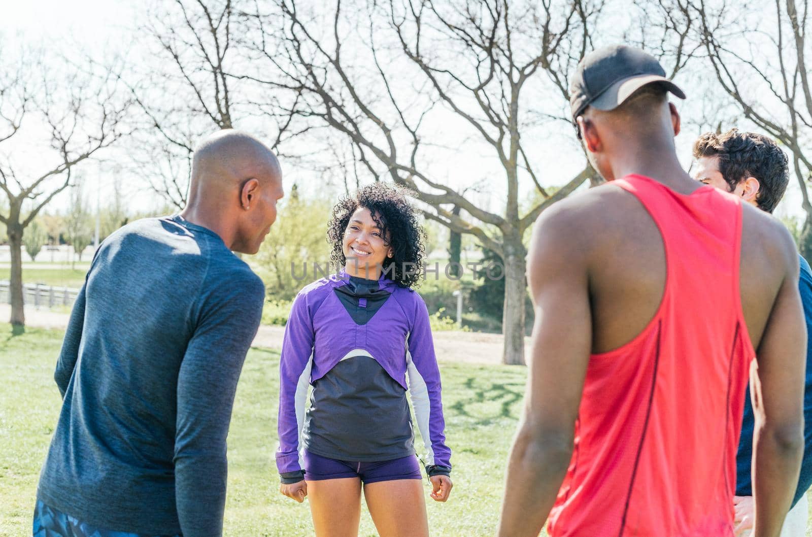 Group of friendly runners talking in a park before training. Selective focus.