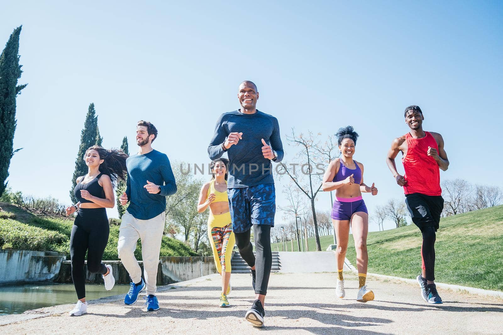 Group of runners training in a park. Front view.