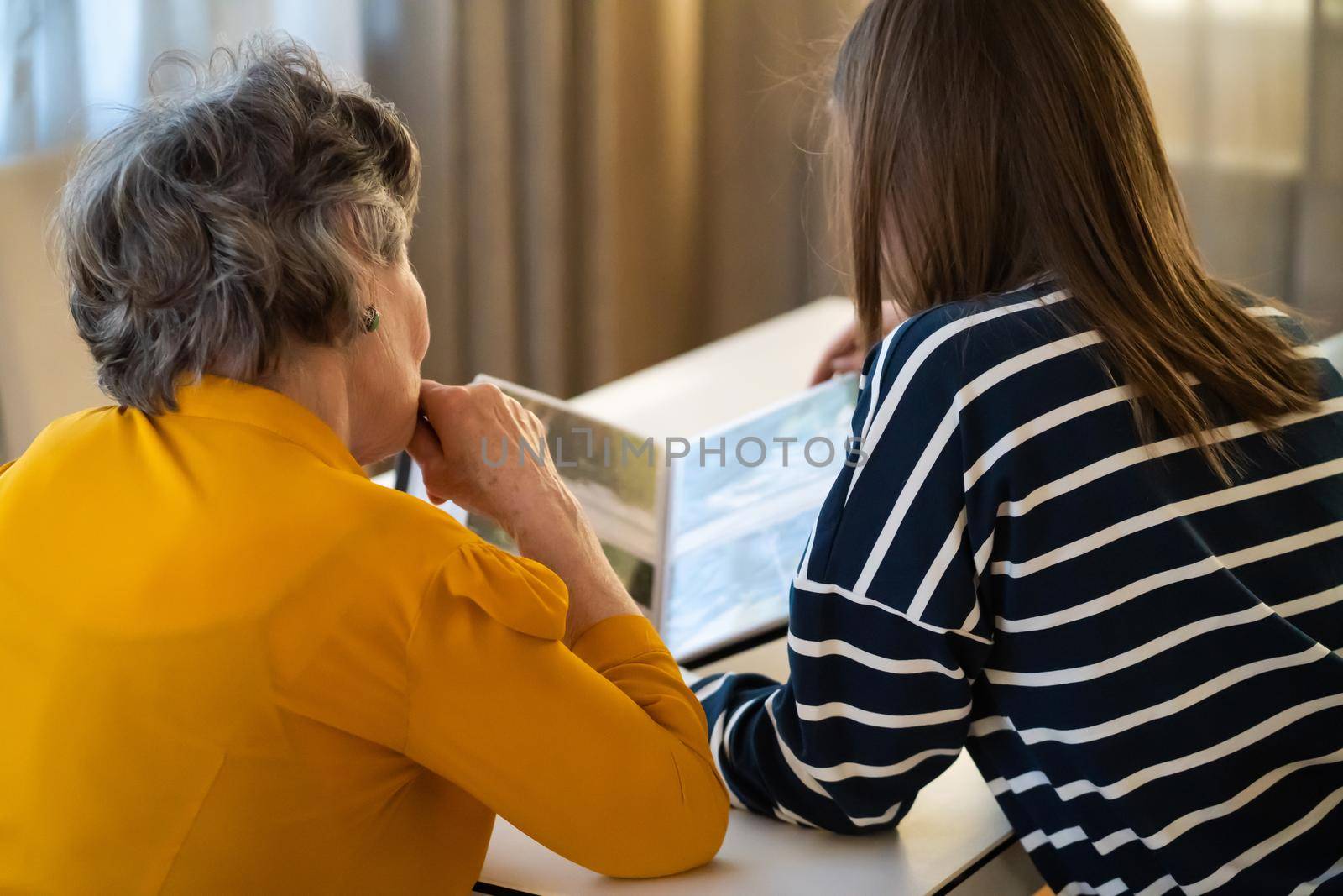 Grandmother and her young granddaughter spent great time together, family members look at photos from the youth of an elderly parent, through the pages of the album and recall funny stories from life.