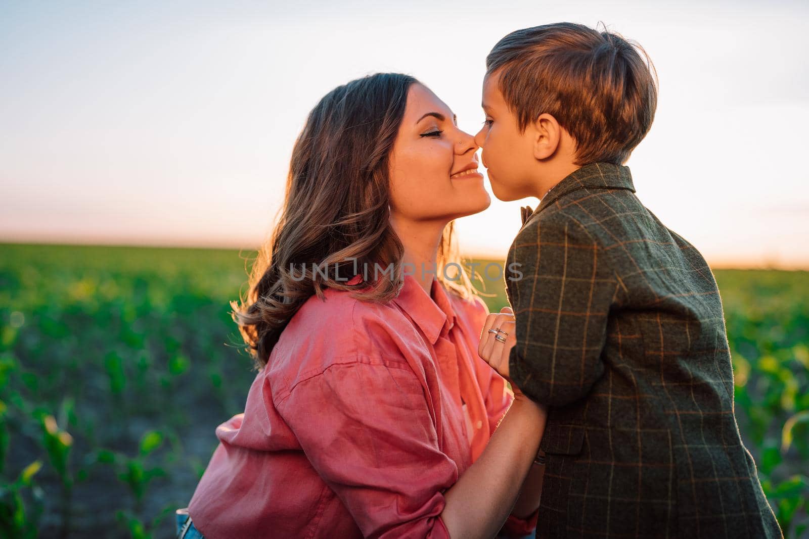 Tender scene of loving son with mom on sunset backdrop. Beautiful family. Cute 3 year old kid with mother. Parenthood, childhood, happiness, children wellbeing concept. High quality photo