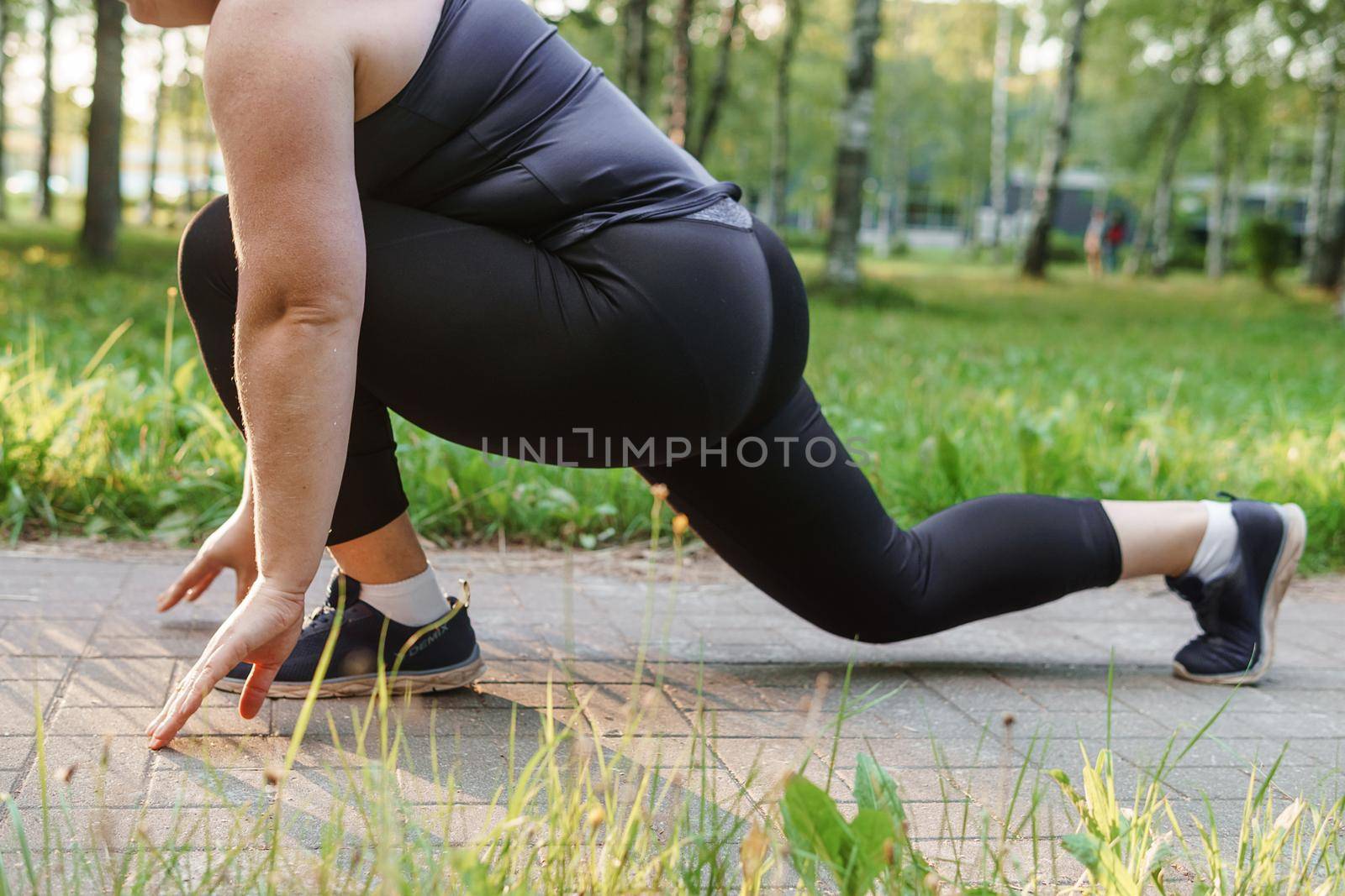 A charming brunette woman plus-size body positive practices sports in nature.