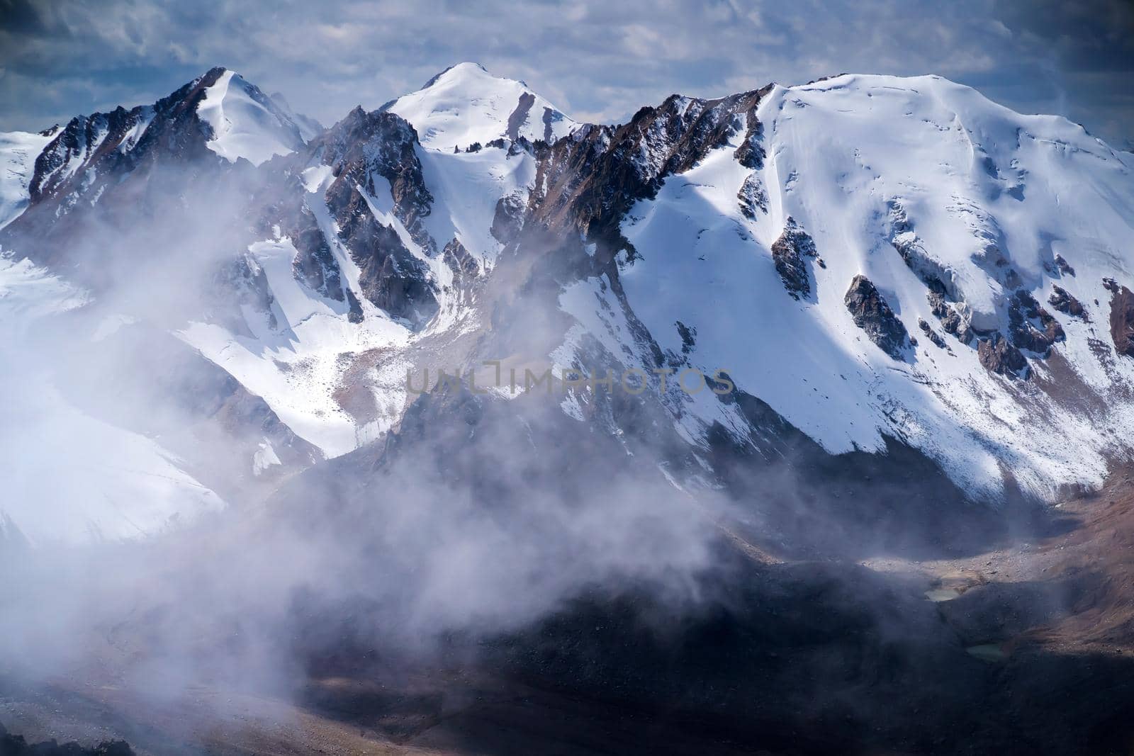Highlands cliffs, snow-capped peaks of mighty mountains in the clouds, a stunning view from above