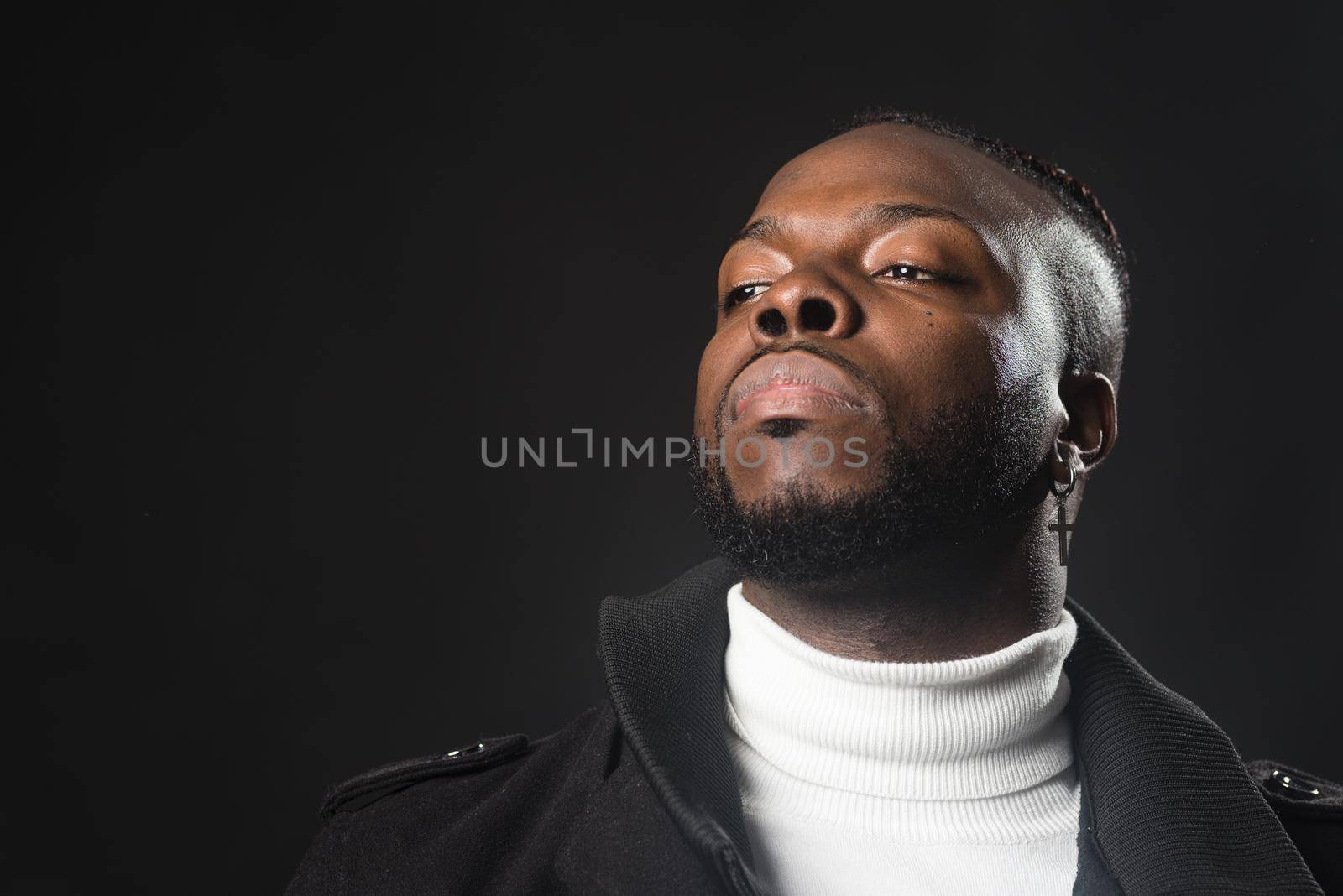 Black man with serious and sad look. Close up. Black background.