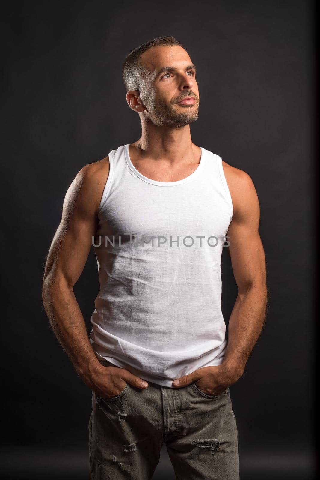 Athletic man in casual clothes. Mid shot. Black background.