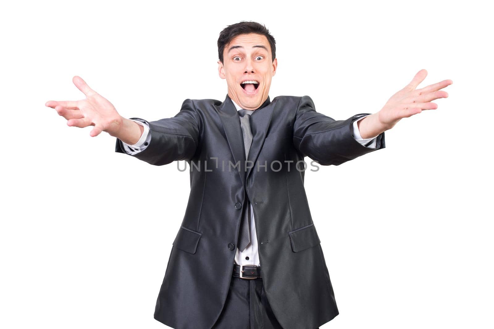 Positive young male entrepreneur with dark hair in classy suit smiling and reaching out arms towards camera against white background