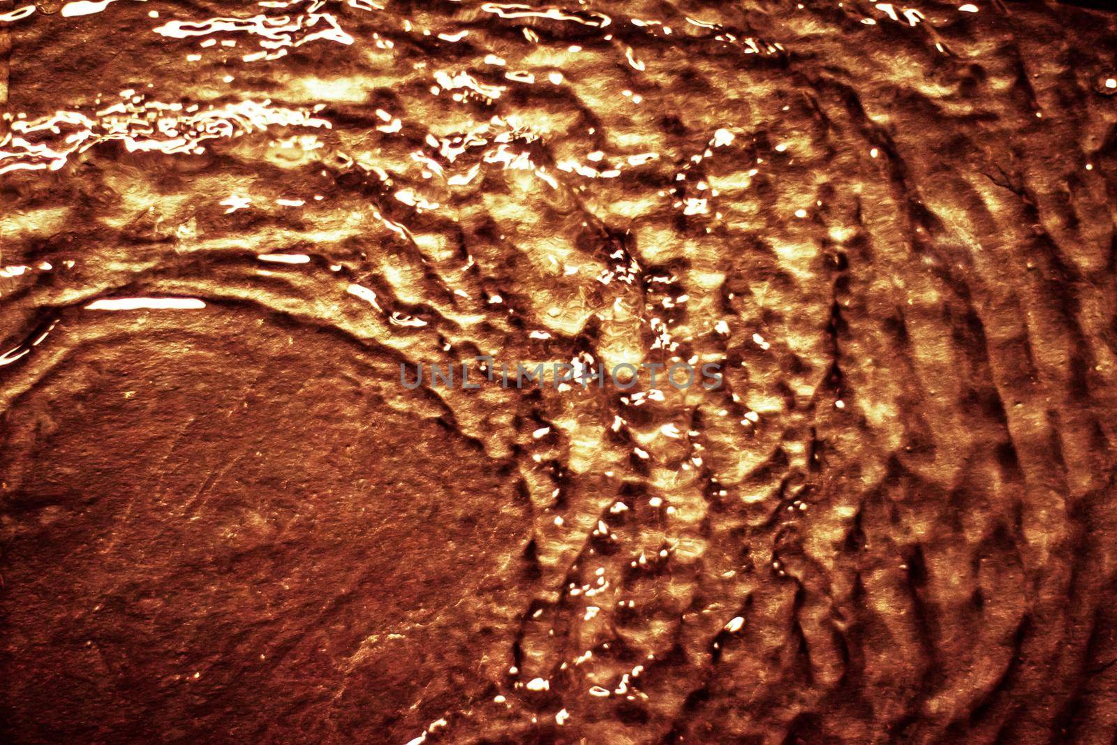 Flowing liquid on gold surface - luxury background and abstract design concept. Golden source