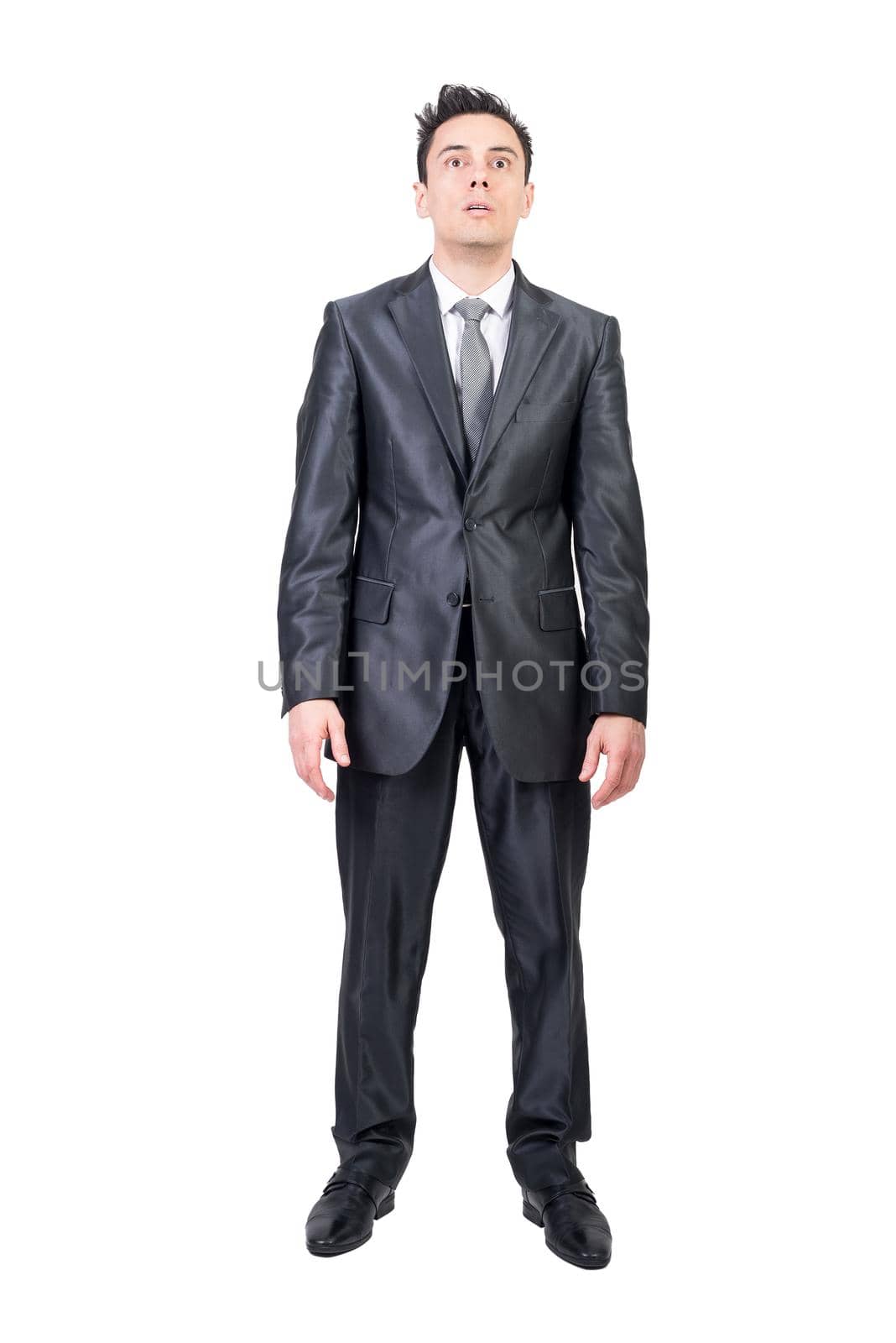 Full body of astonished male entrepreneur in formal suit looking forward with opened mouth on white background