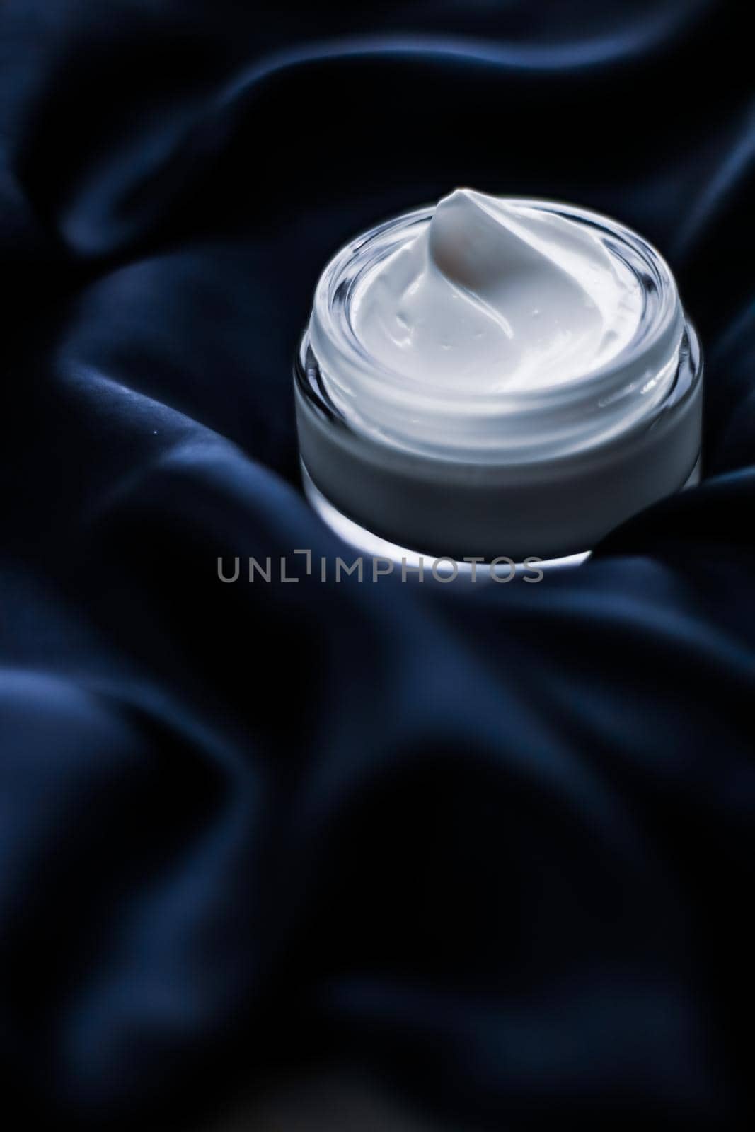 Beauty, anti-age cosmetics and skincare concept - Luxury face cream jar on a dark blue silk