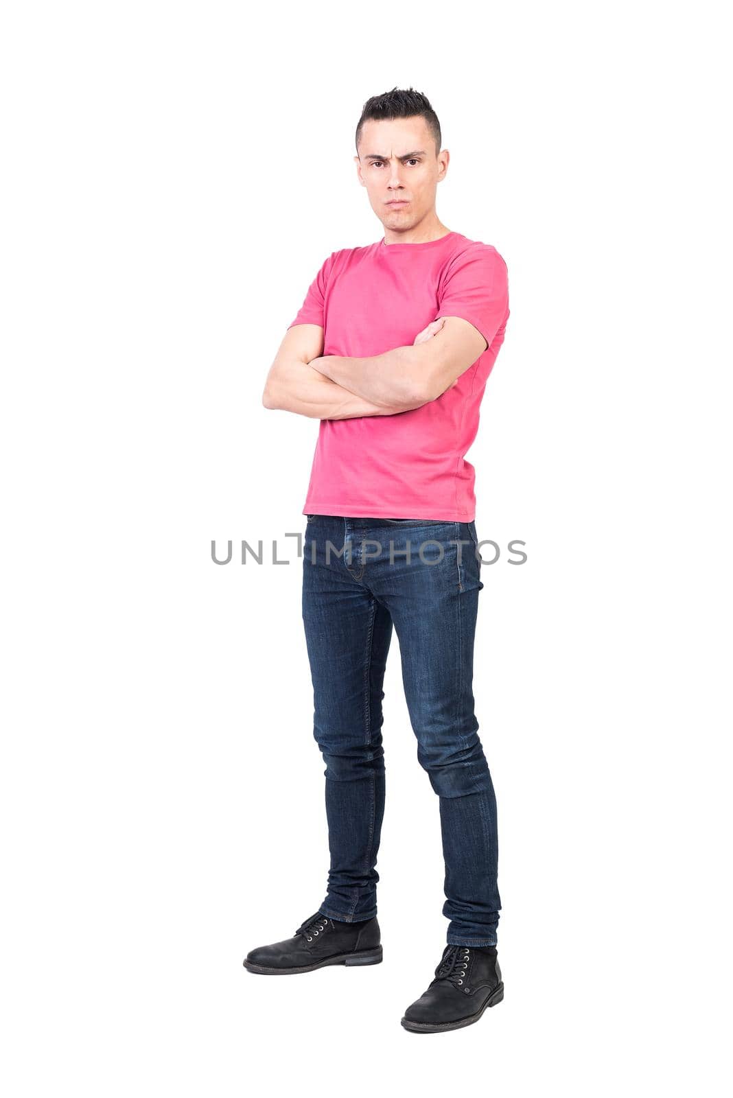 Full body of serious male model in casual outfit standing against white background and looking at with self assured face