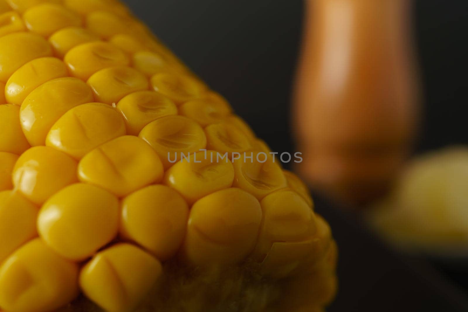 close-up macro shot of a fresh ear of corn with an out-of-focus pepper pot in the background