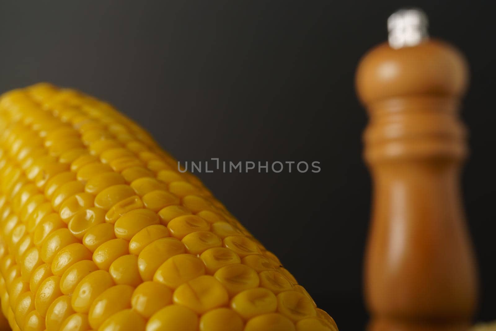 macro close-up of an ear of corn with an out-of-focus pepper pot in the background by joseantona