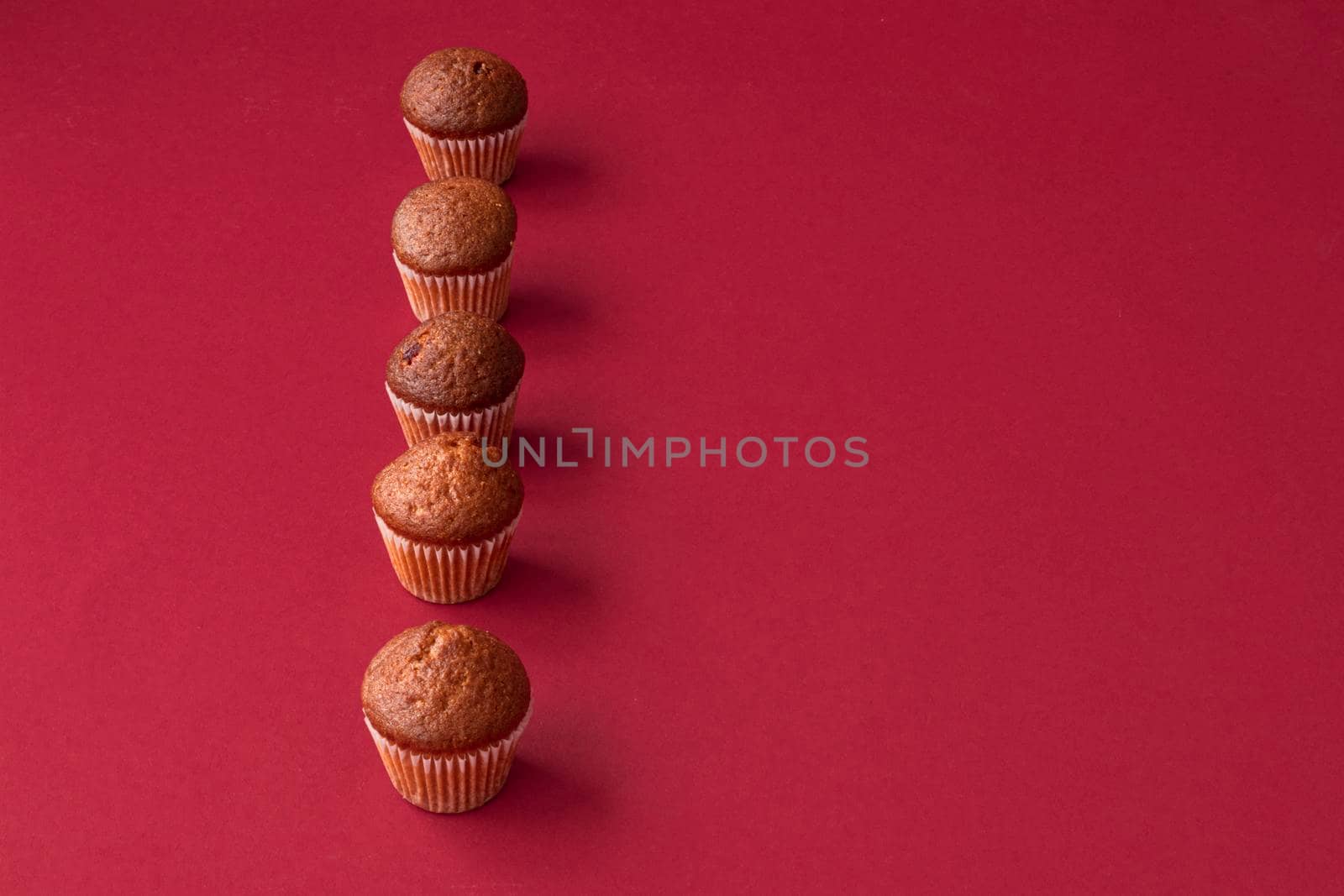 vanilla mini muffins on a red background. Place for your text. Cupcake pattern by Suietska
