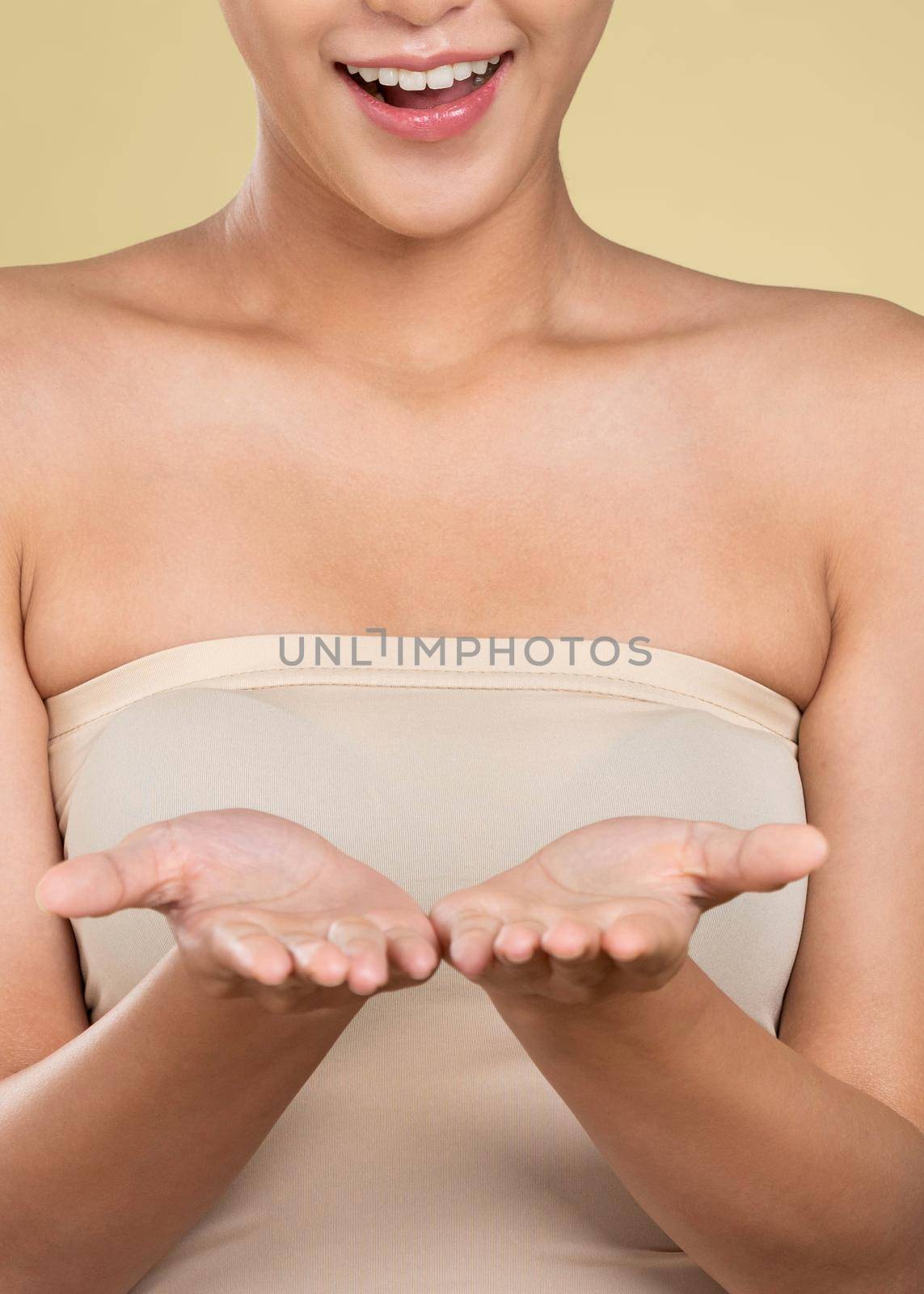 Closeup ardent woman holding empty space for product, advertising text place, isolated background. Concept of healthcare advertising for skincare, beauty care product. No face.