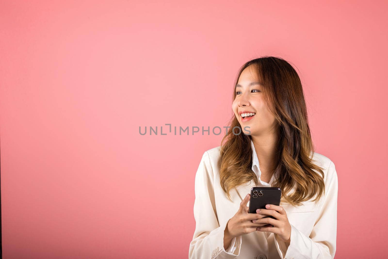 Female surprised and sms chatting internet online on smartphone studio shot isolated on pink background, Happy Asian portrait beautiful cute young woman teen smiling excited hold smart mobile phone