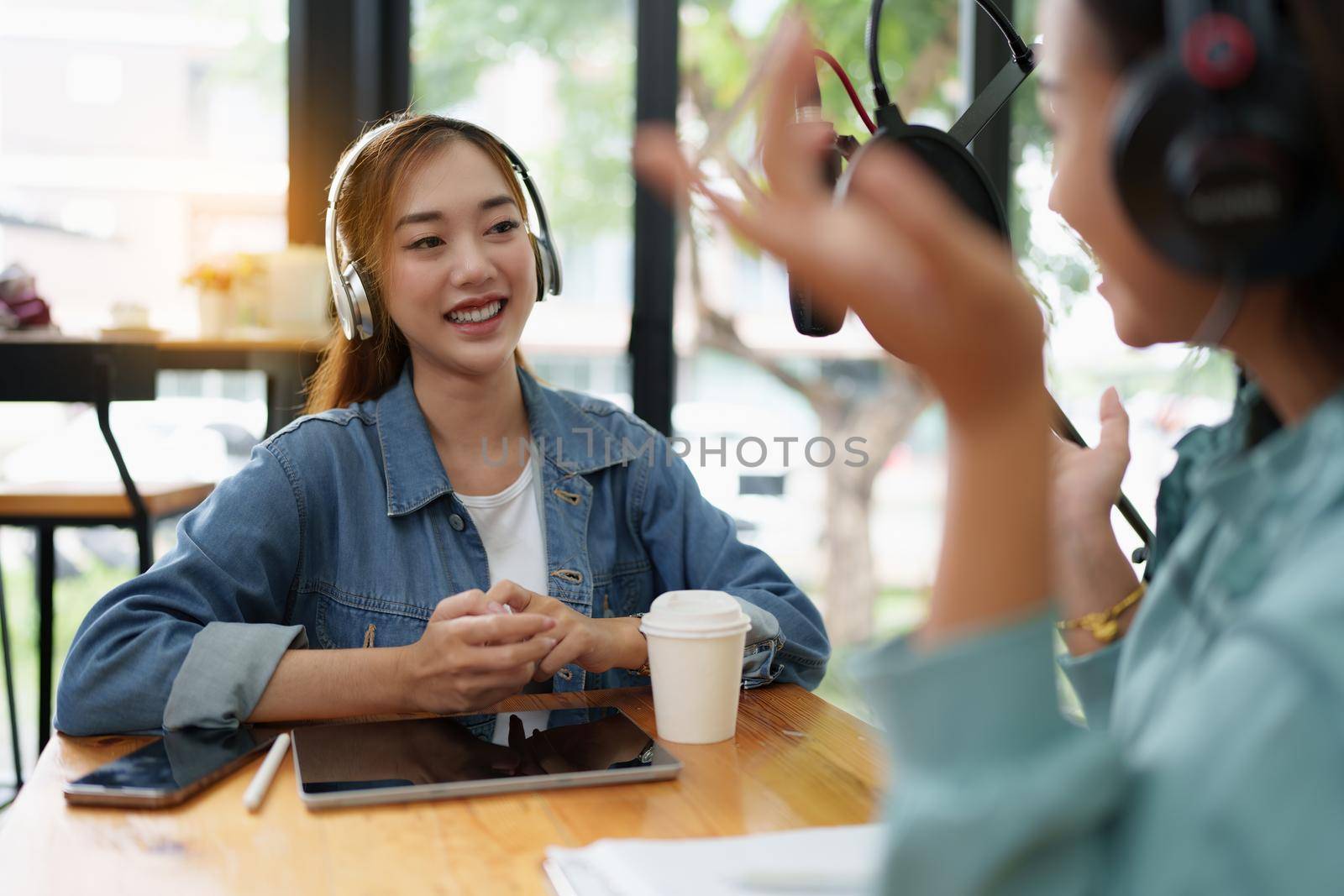 Asian podcaster making audio podcast working with guest at home studio.