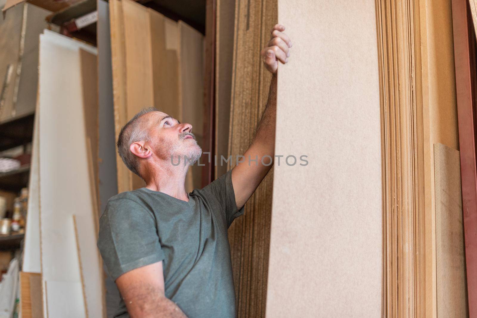 Worker man selecting a long MDF plank along others boards