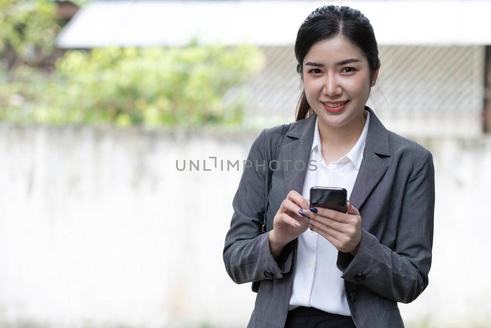 Portrait of a beautiful smiling woman using a mobile phone outdoors by wichayada