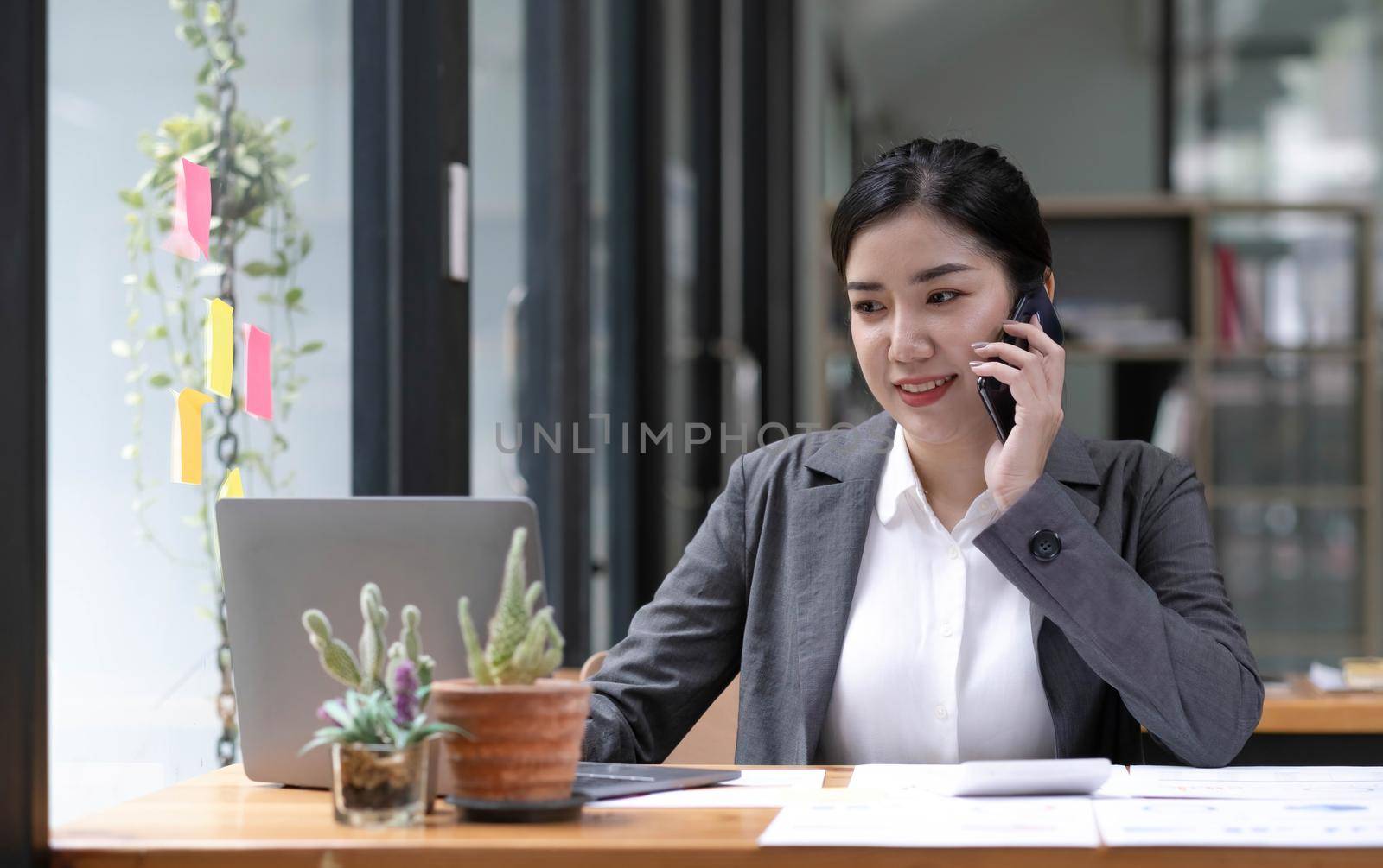 Asian business woman have the joy of talking on the phone, laptop and tablet on the office desk. by wichayada