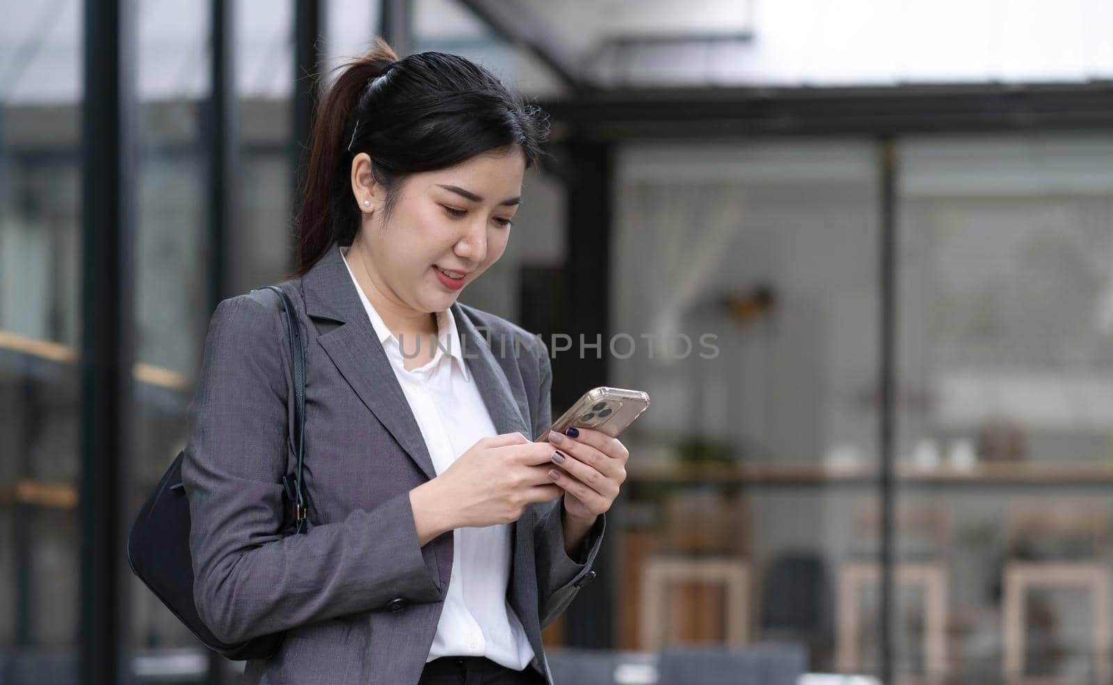 Portrait of a beautiful smiling woman using a mobile phone outdoors by wichayada