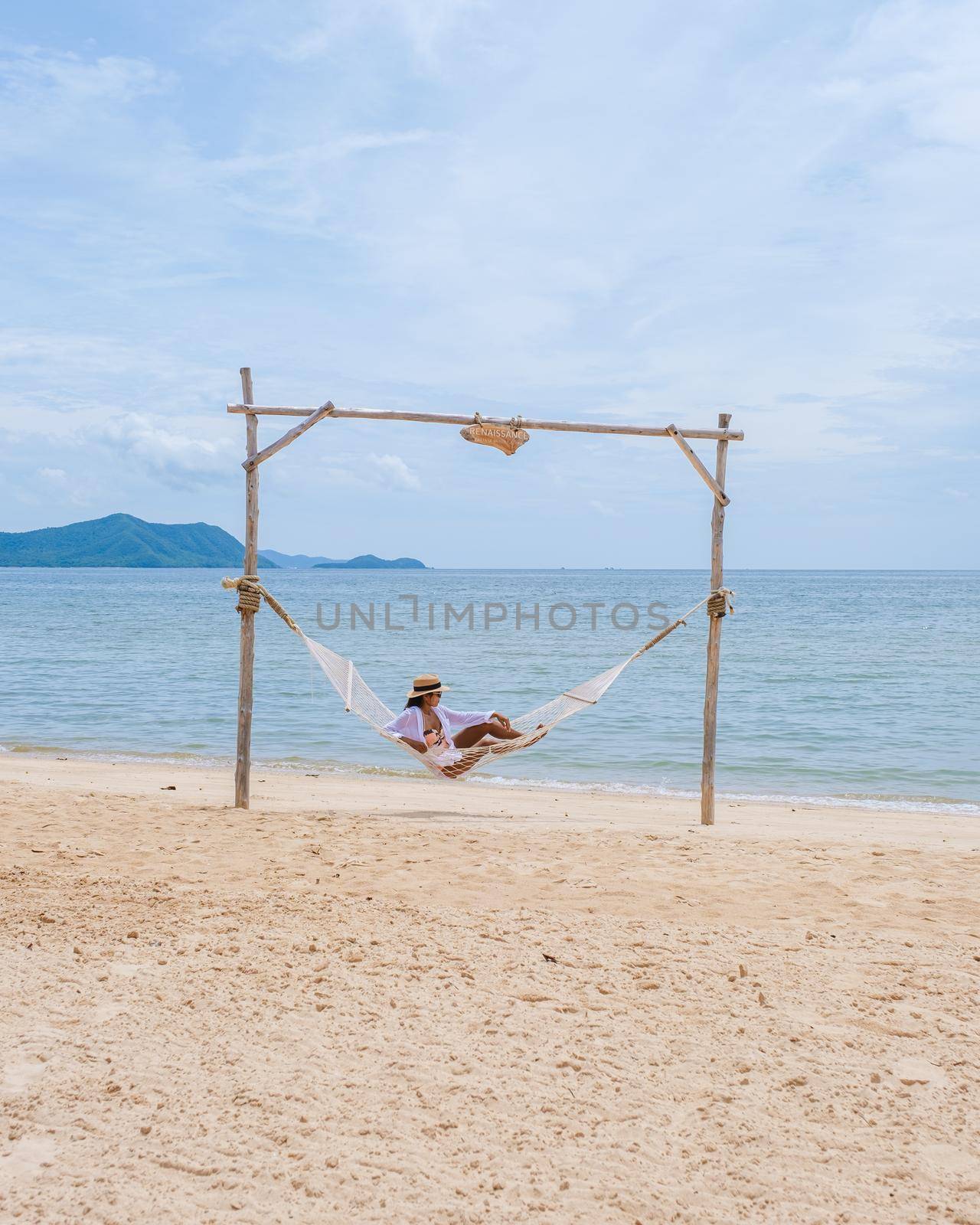Women on the beach on a sunny day with a hammock on the beach in Pattaya Thailand Ban Amphur beach. Asian women on a tropical beach with palm trees and hammocks