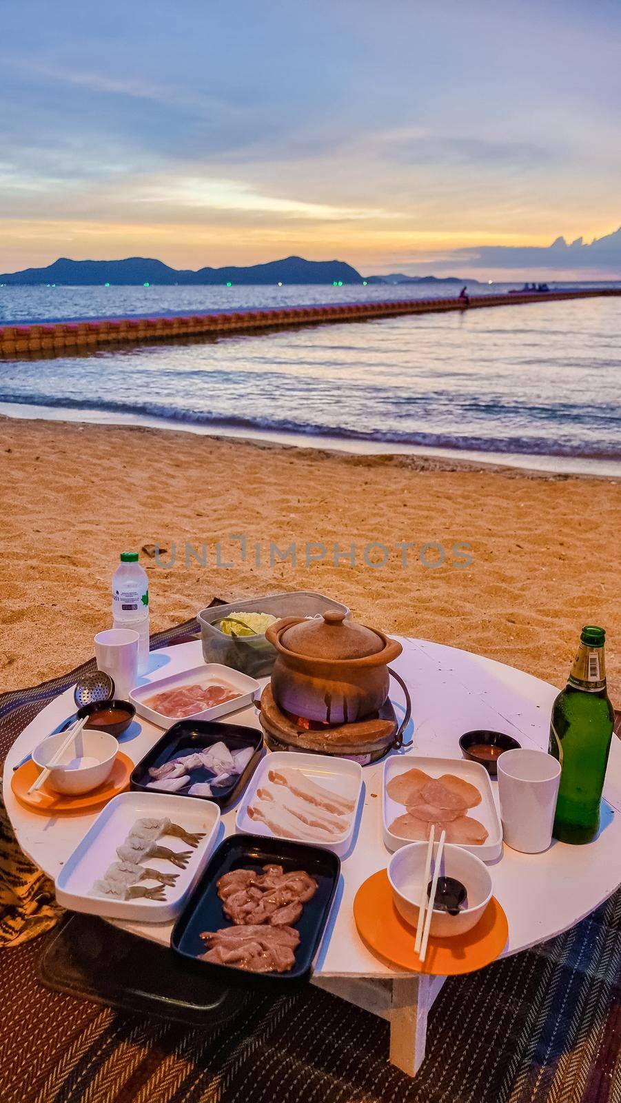 women bbq cooking noodle soup during sunset in Thailand Ban Amphur beach. relaxing with bbq Thai traditional on a tropical beach with palm trees and hammock during sunset