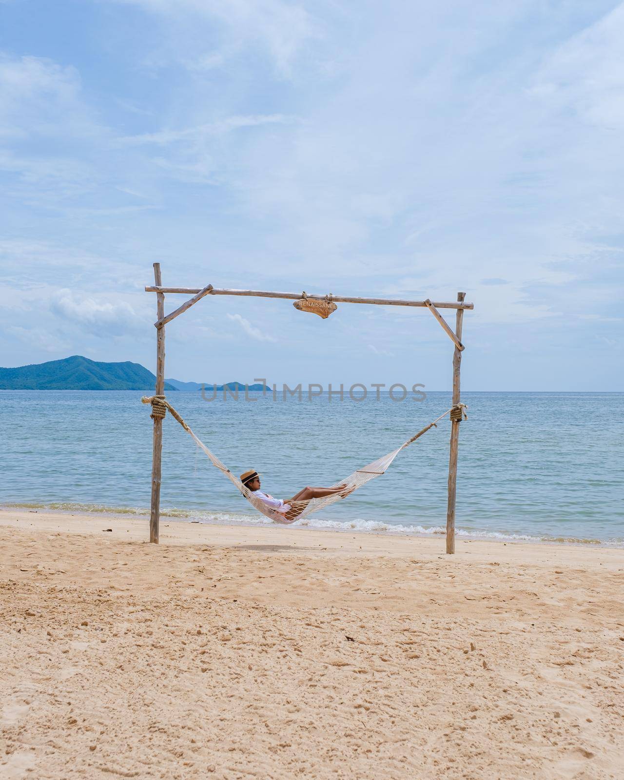 Women on the beach on a sunny day with a hammock on the beach in Pattaya Thailand Ban Amphur beach. Asian women on a tropical beach with palm trees and hammocks