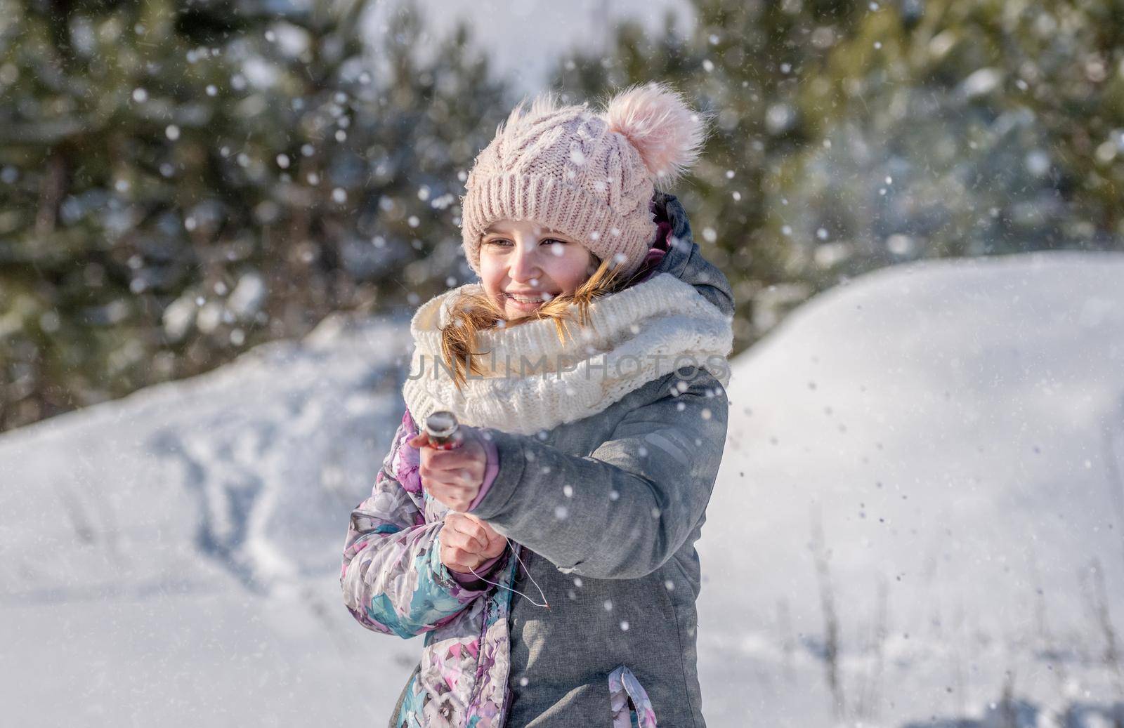 Preteen girl child playing in winter snow time outdoors and smiling. Pretty female kid enjoying cold weather
