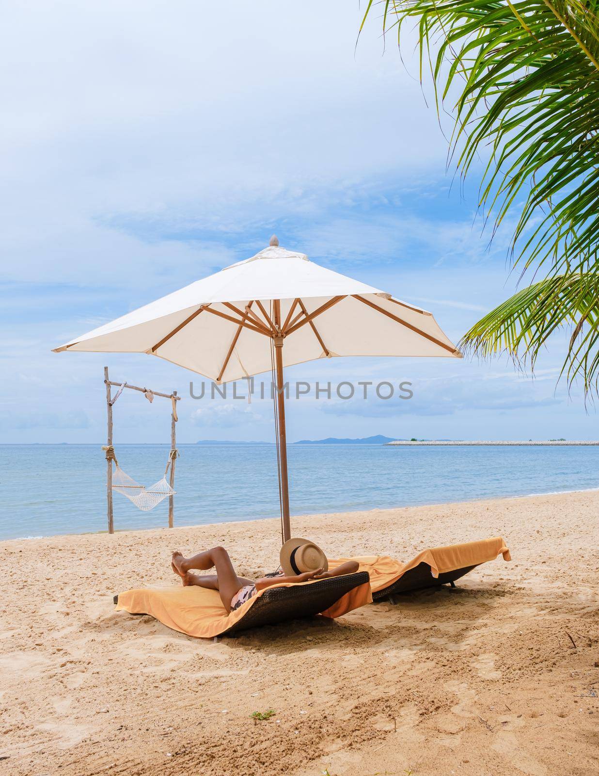 Women relaxing on a beach chair sunny day with hammock on beach in Pattaya Thailand Ban Amphur beach by fokkebok