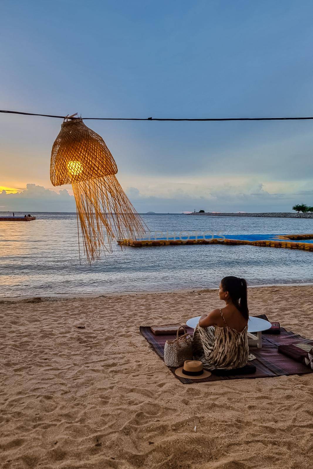 women bbq cooking noodle soup during sunset in Thailand Ban Amphur beach. relaxing with bbq Thai traditional on a tropical beach with palm trees and hammock during sunset
