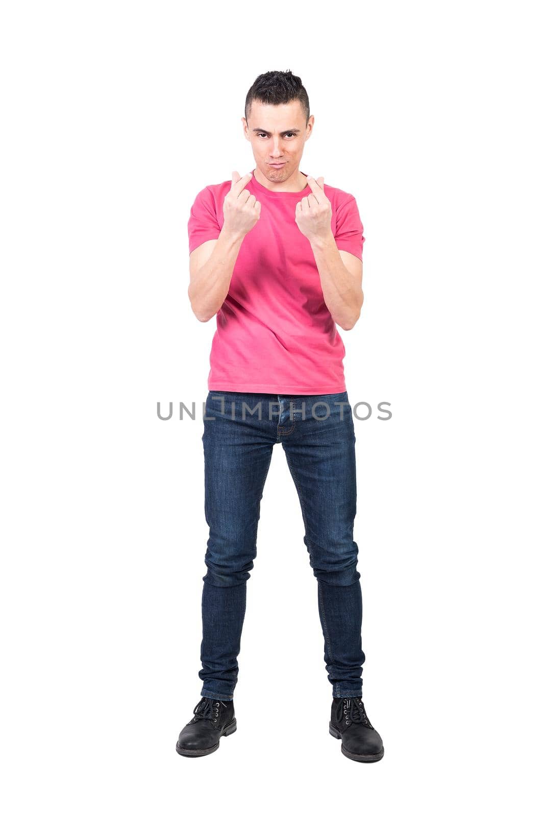 Full length self assured male in jeans and pink t shirt looking at camera and making money gesture against white background