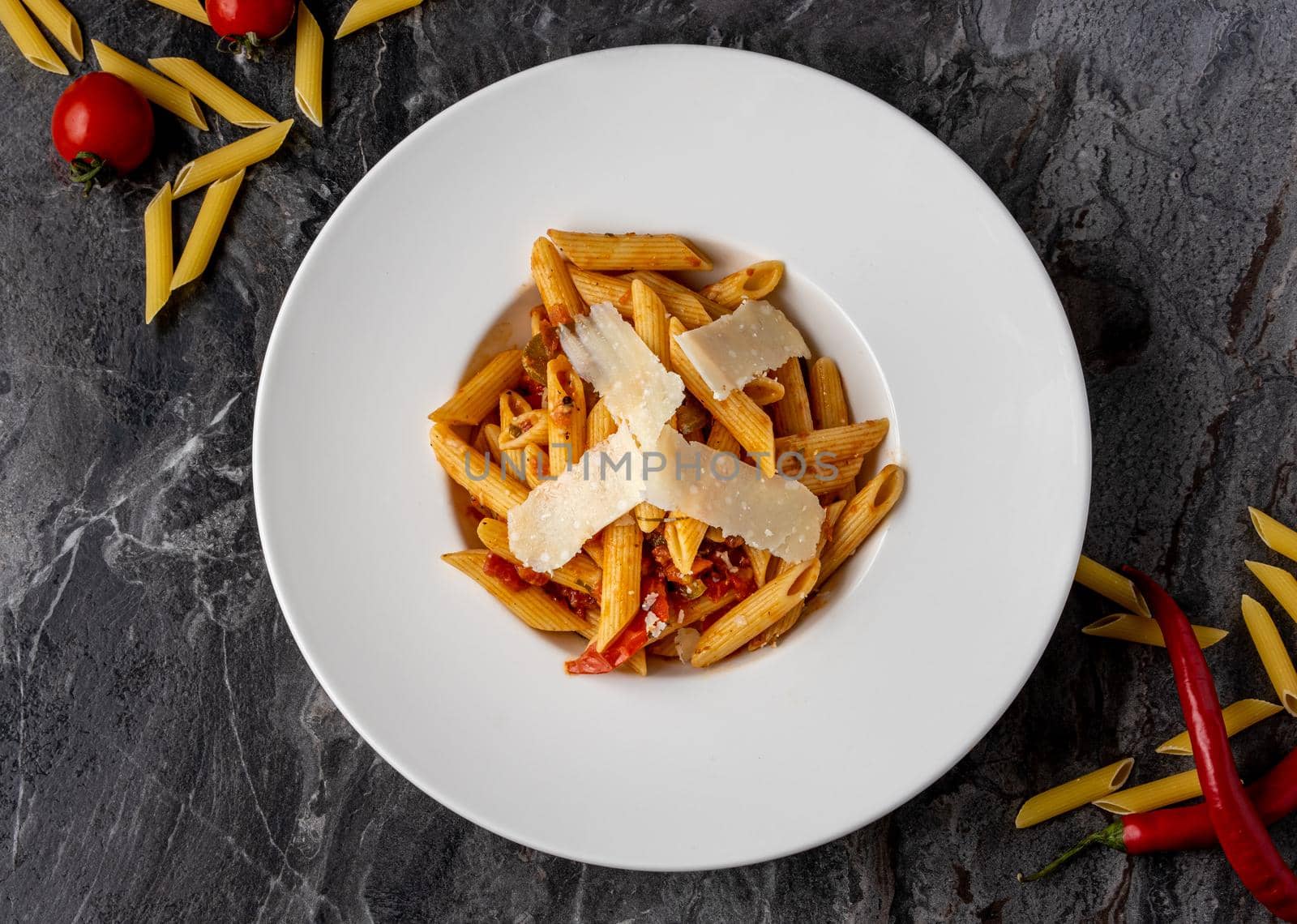 Penne pasta with a spicy sauce, chili pepper and grated parmesan cheese