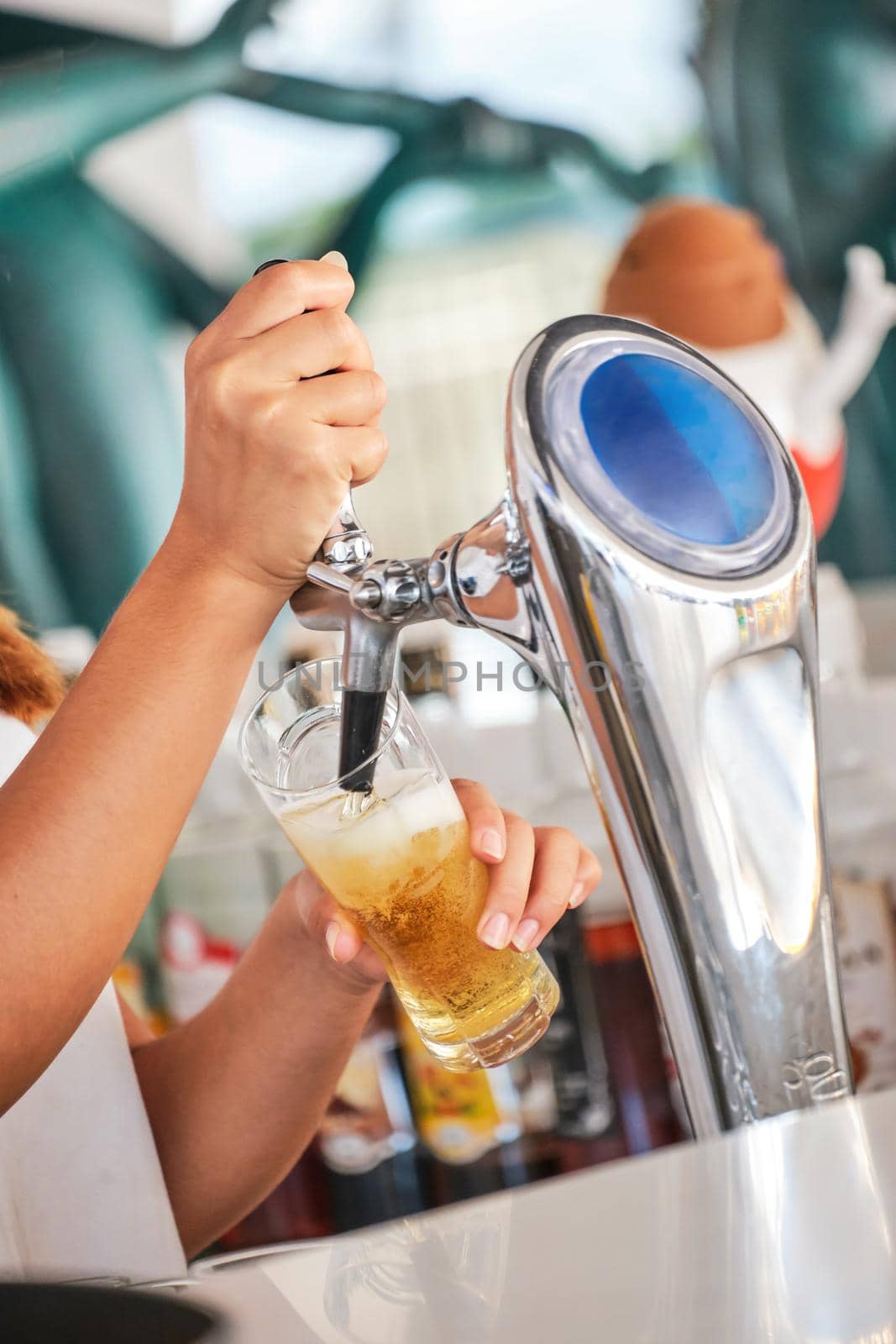 We meet oktoberfest. Hand of bartender pouring a large lager beer in tap. Pouring beer for client. Side view of young bartender pouring beer while standing at the bar counter