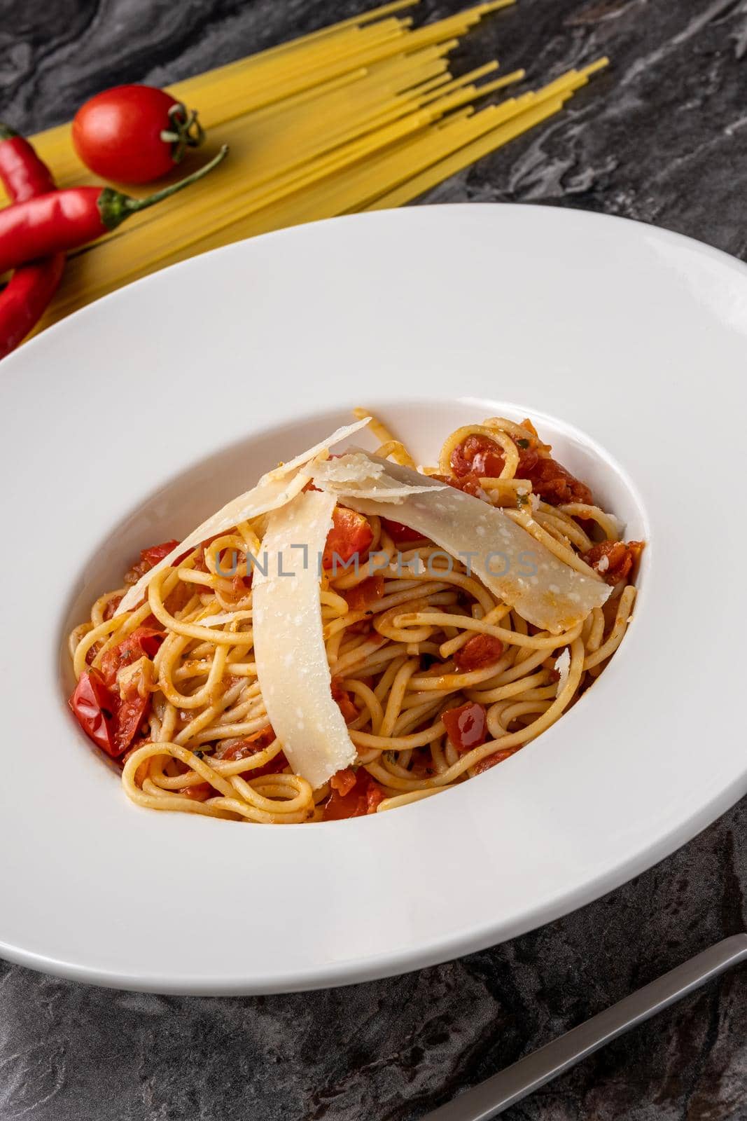 Spaghetti with a spicy sauce, chili pepper and grated parmesan cheese