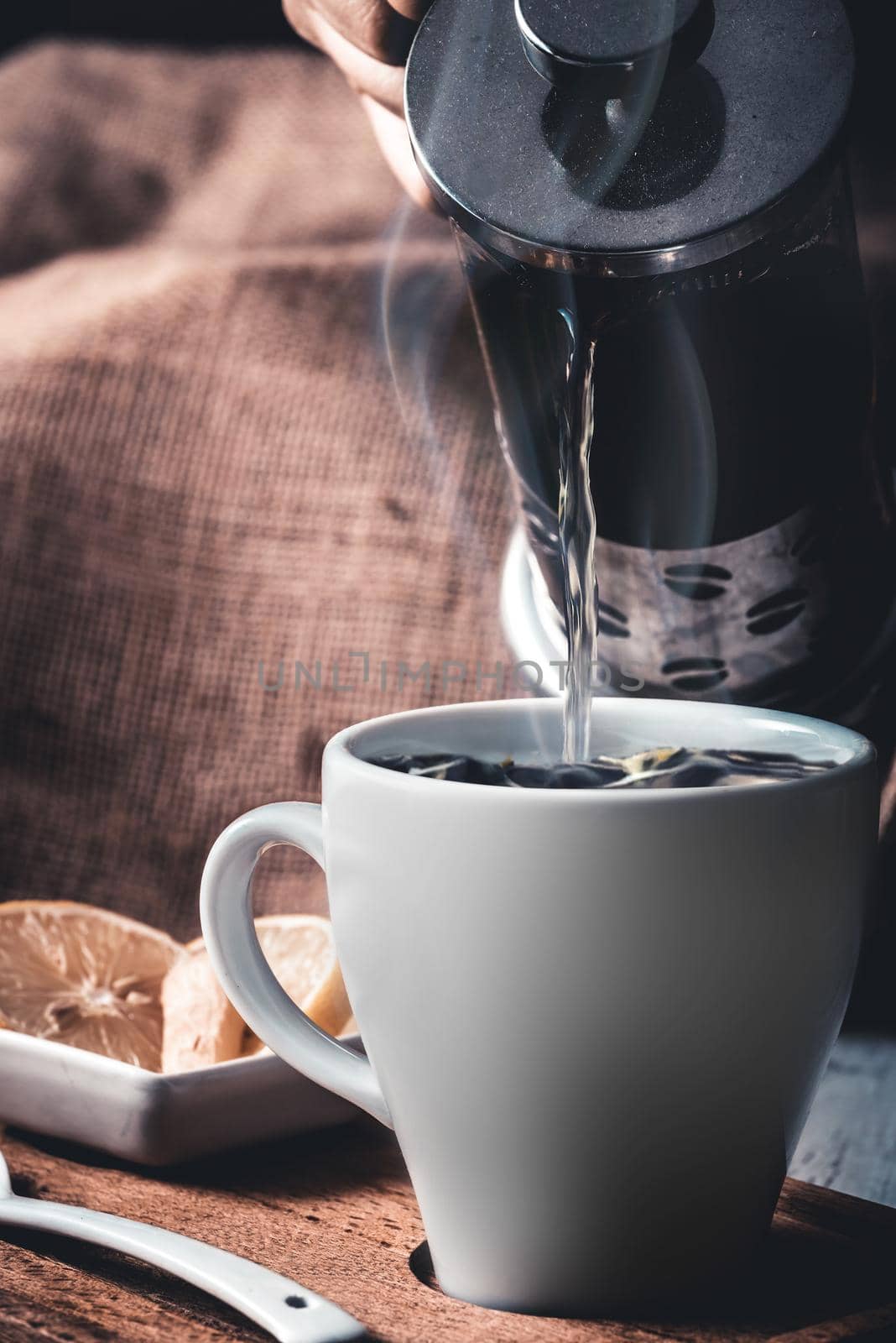 Pouring hot herbal tea into white mug