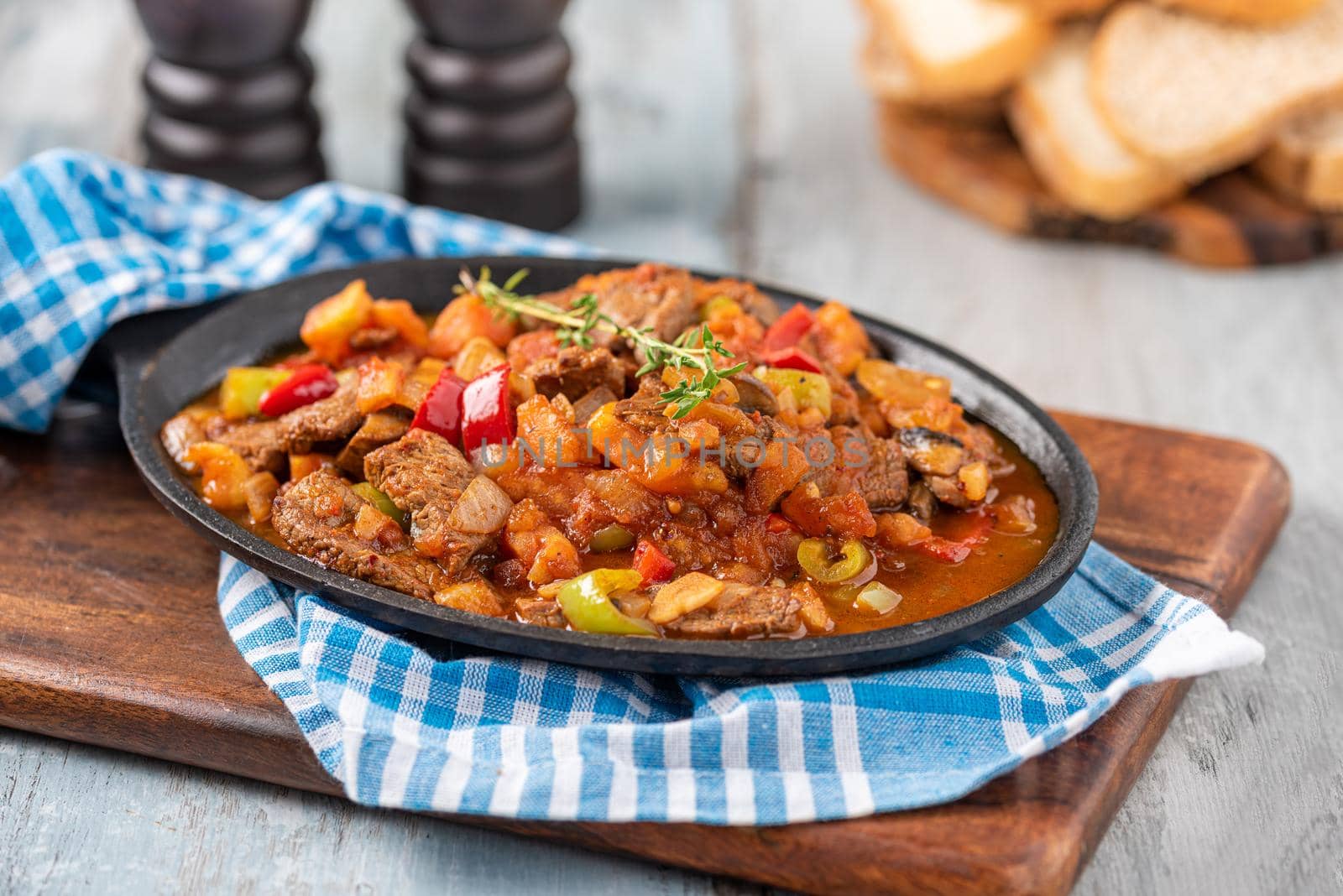 Beef stew with potatoes, carrots and herbs in iron casserole, top view