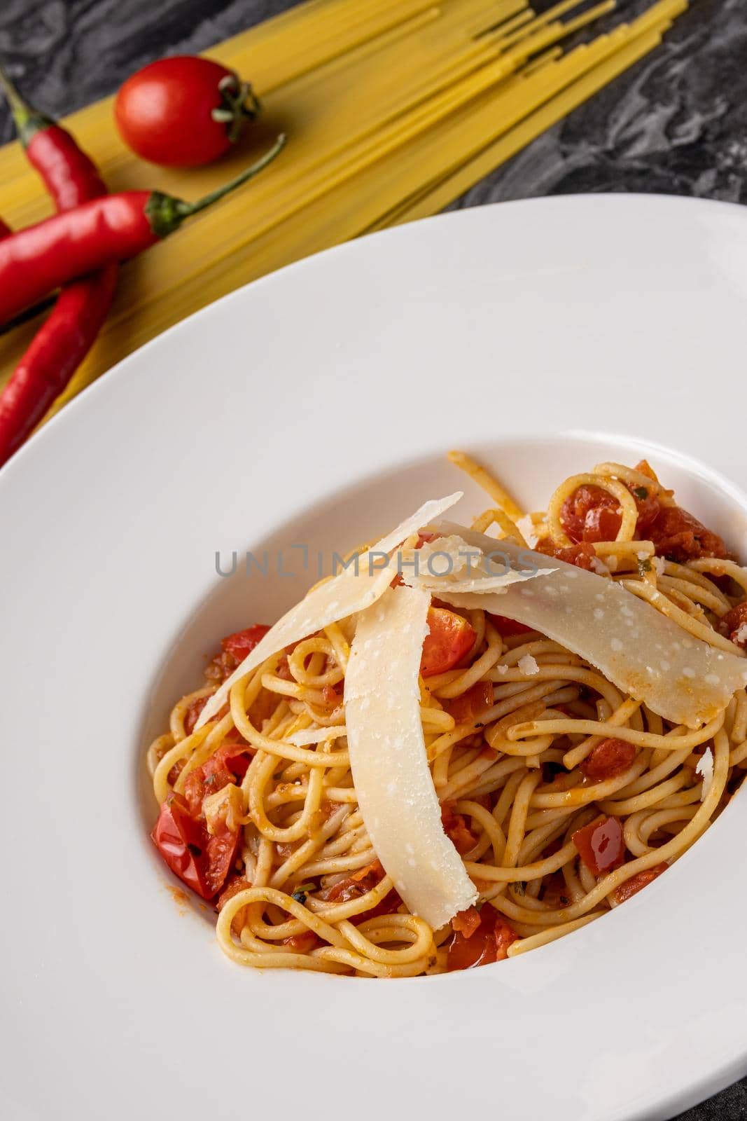 Spaghetti with a spicy sauce, chili pepper and grated parmesan cheese