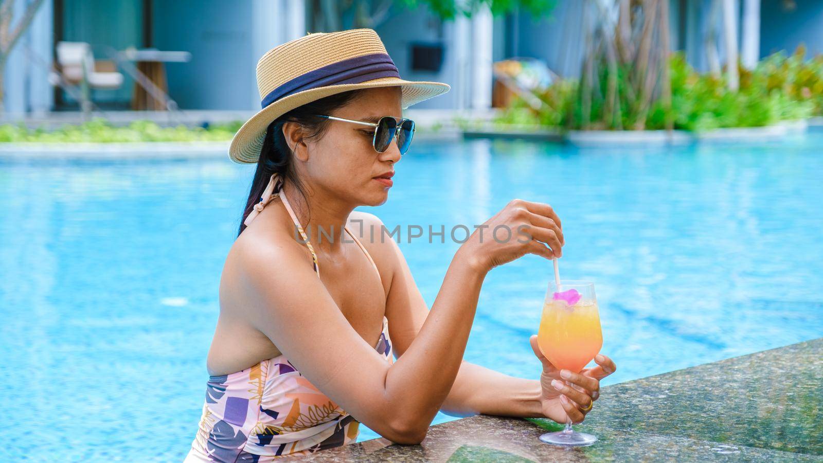 Asian women with hat and cocktail in hand relaxing in swimming pool, banner holiday vacation concept by fokkebok