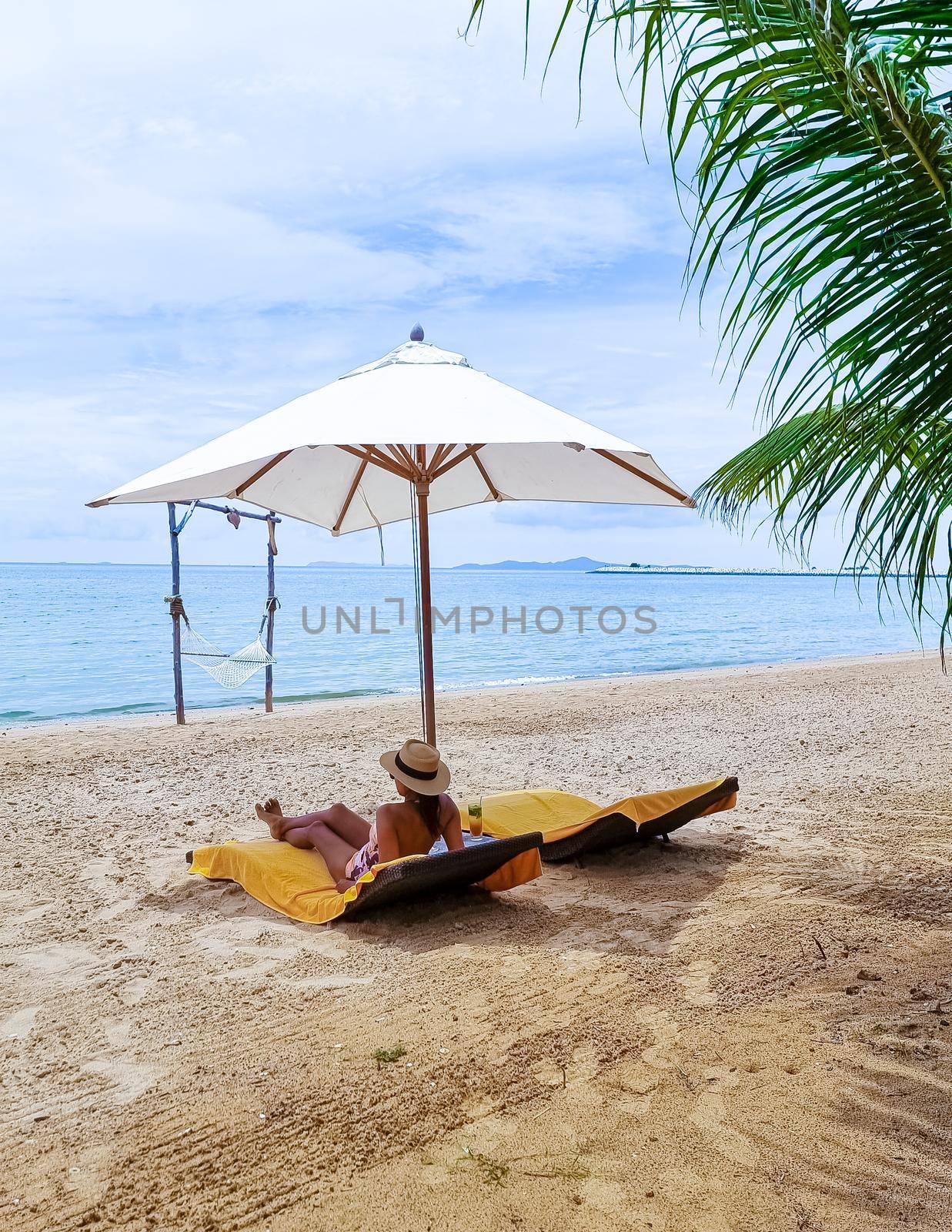 Women relaxing on a beach chair sunny day with a hammock on the beach in Pattaya Thailand Ban Amphur beach